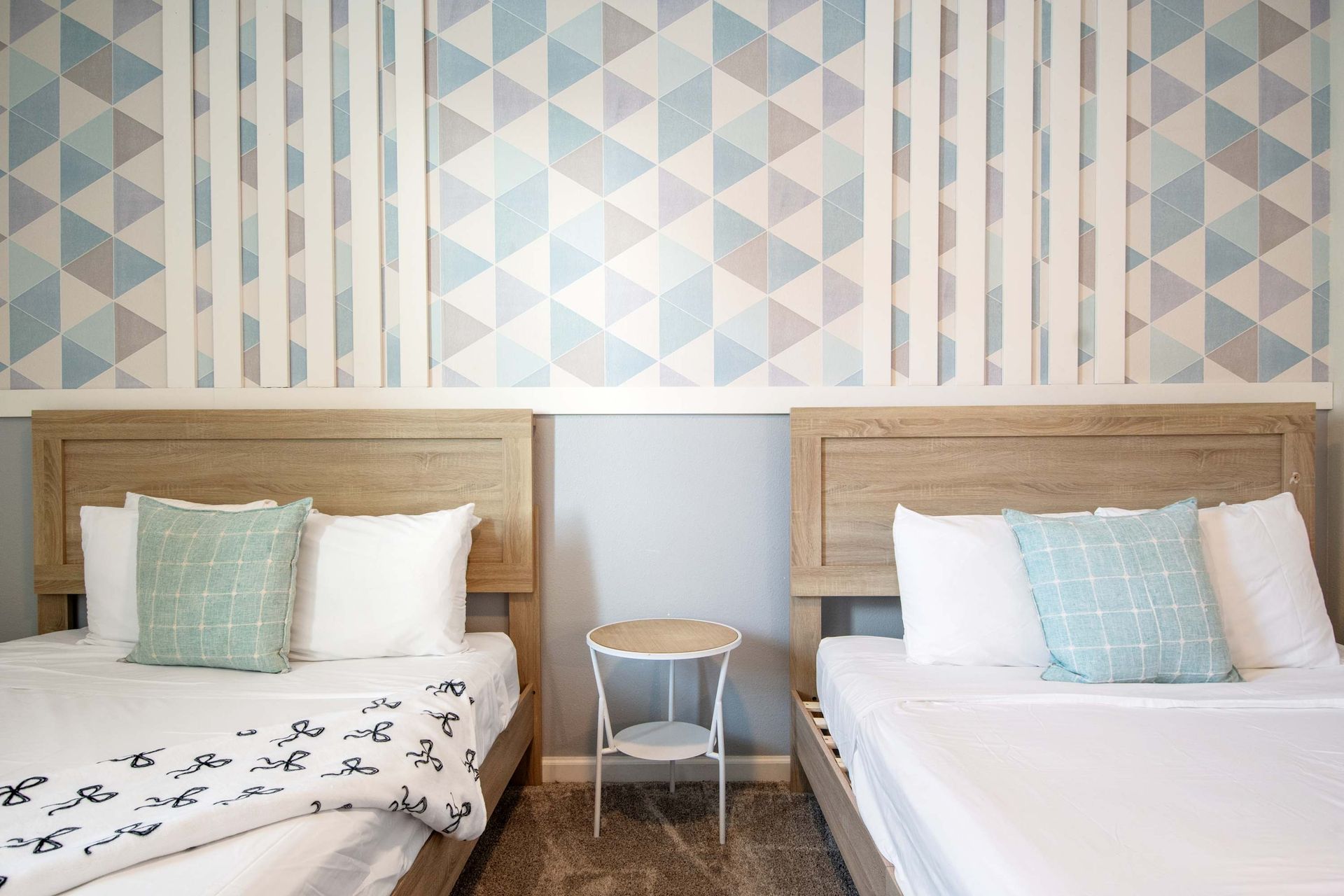 Twin Queen beds with soothing blue/white geometric accent wall.