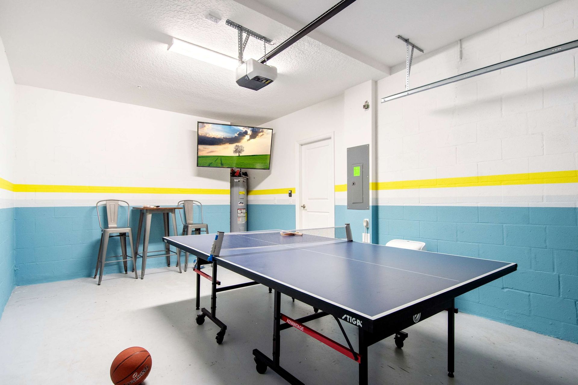 Vibrant blue and yellow game room with table tennis and bar seating.