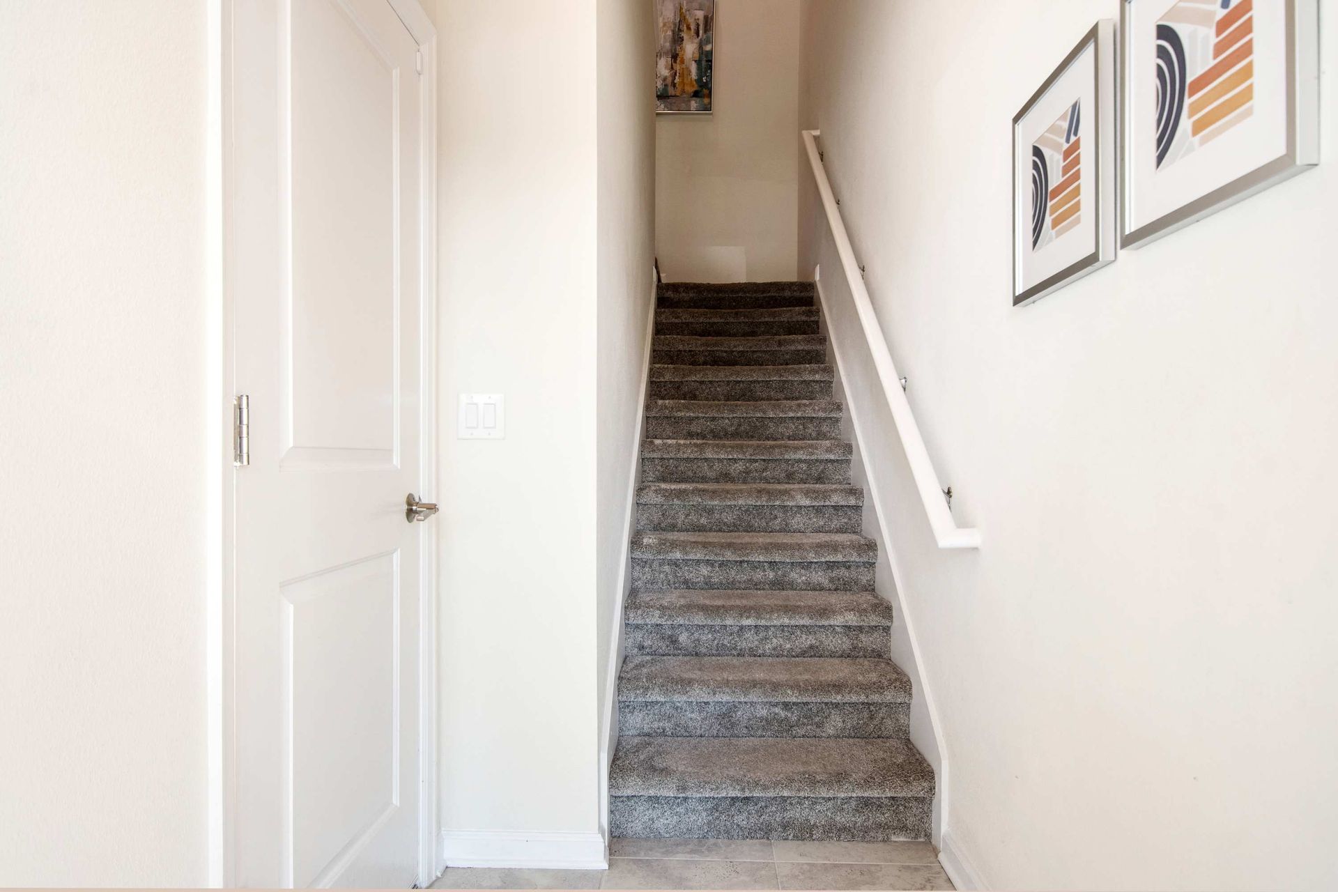 Carpeted stairs and white walls in a clean, modern entryway.
