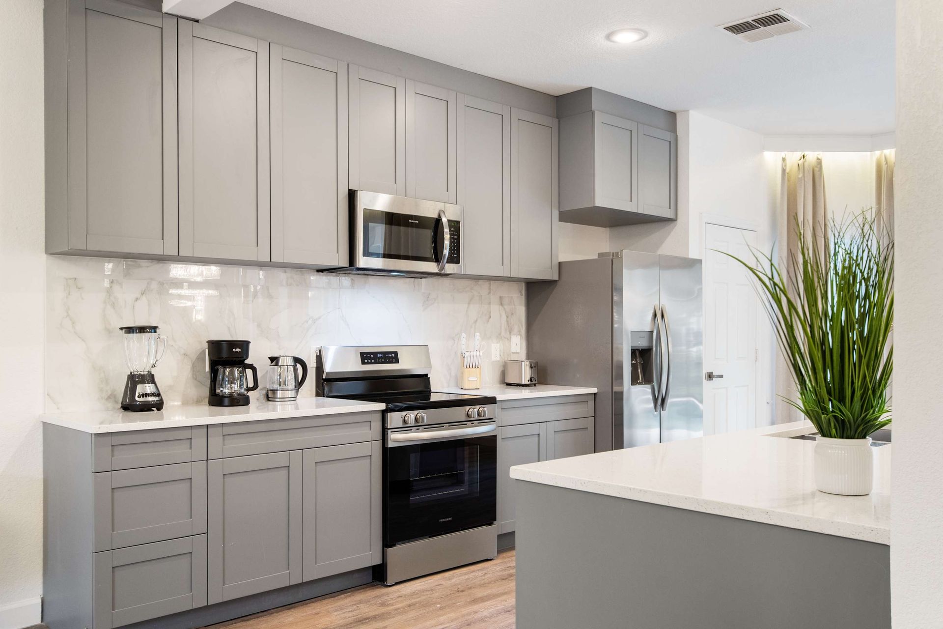 Sleek gray cabinetry, marble backsplash, and stainless steel appliances. 