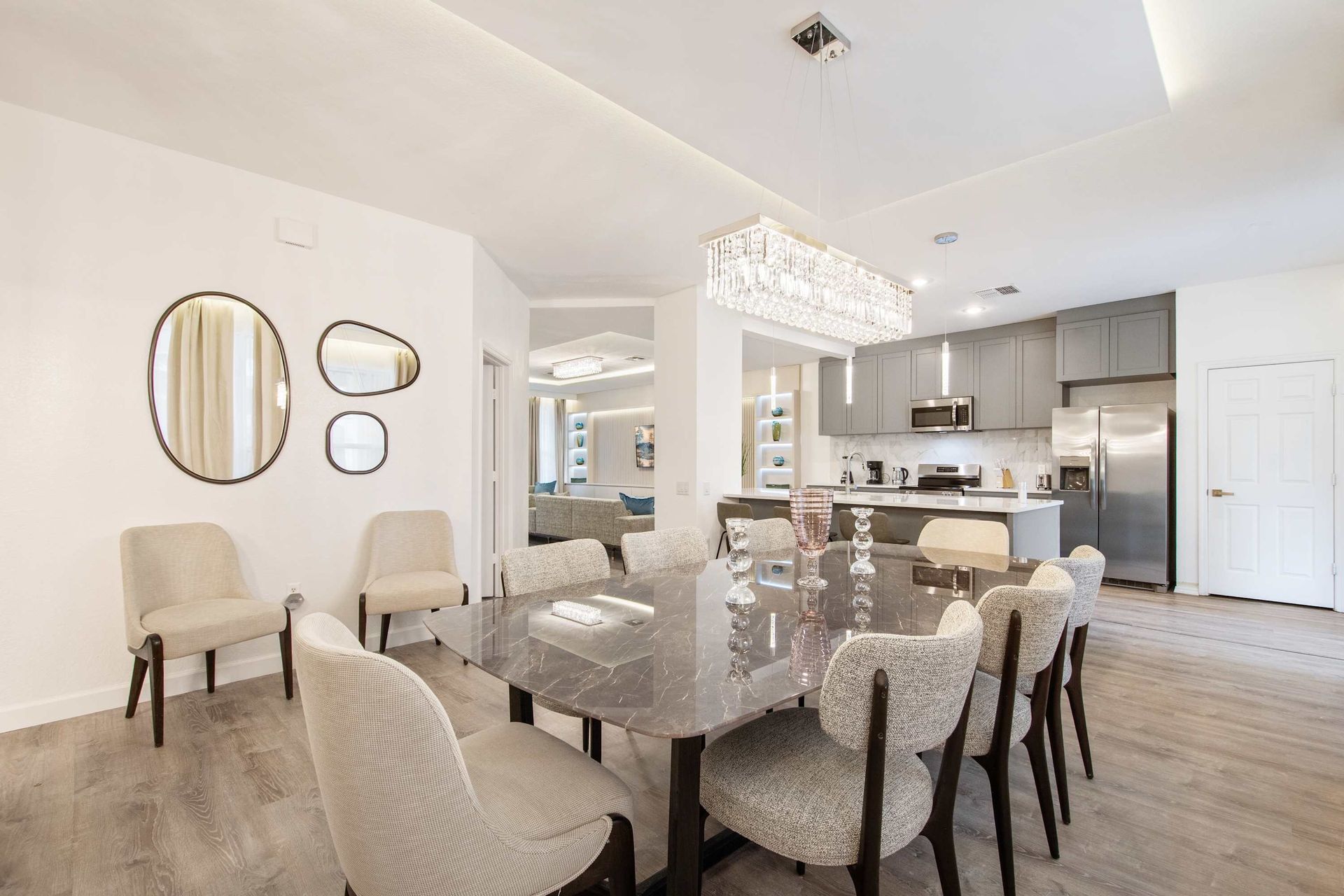 Modern dining for eight, flowing into a sleek gray kitchen.