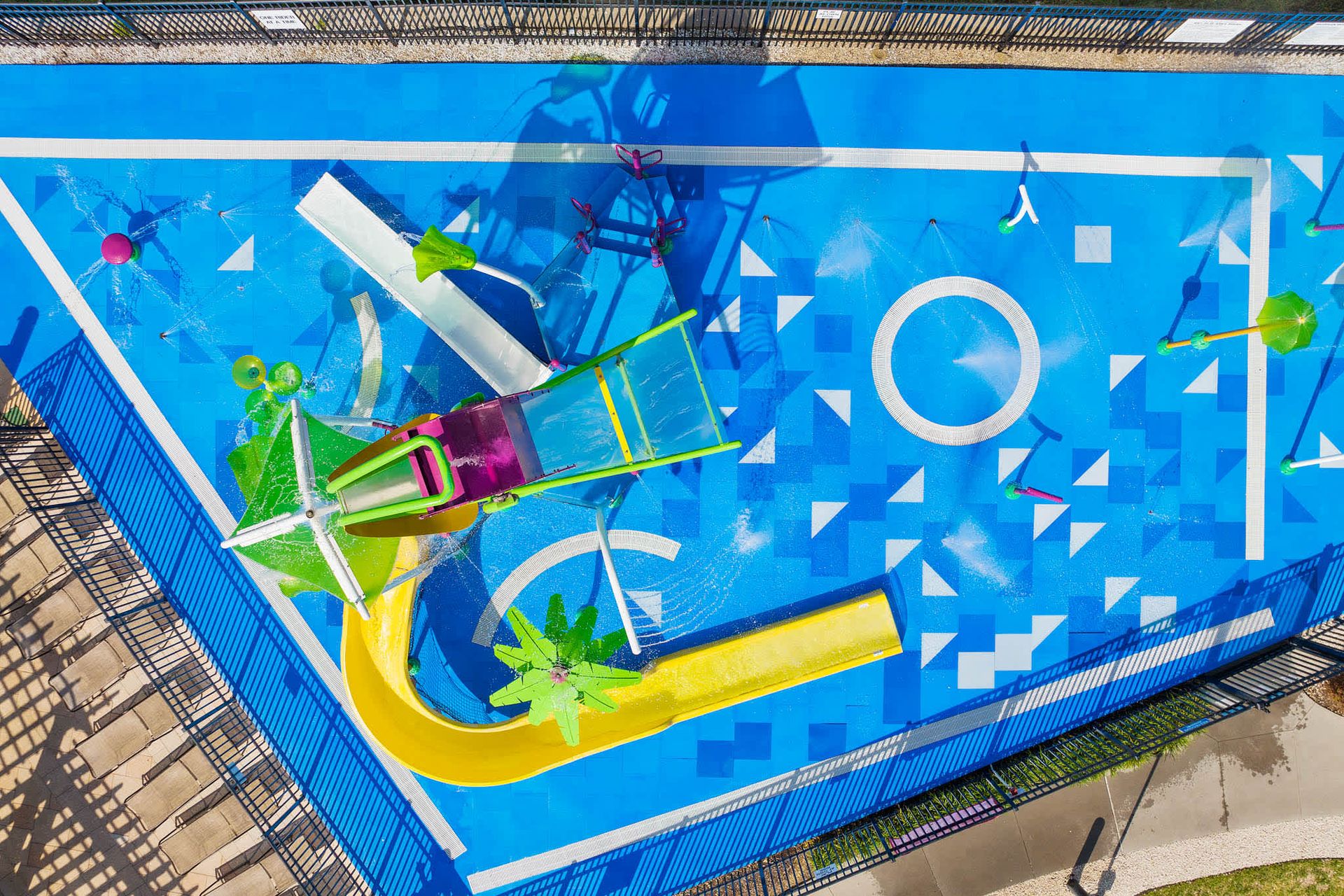 Colorful resort splash pad with fountains and mini slides for hours of fun.