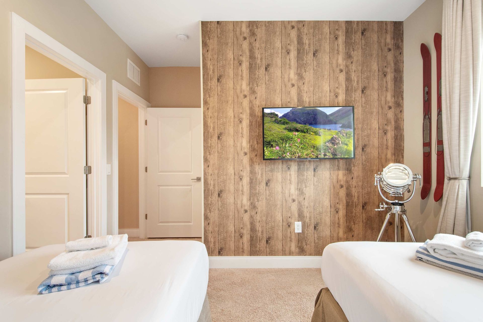 Rustic chic twin room: wood accent wall, TV, and vintage ski decor.