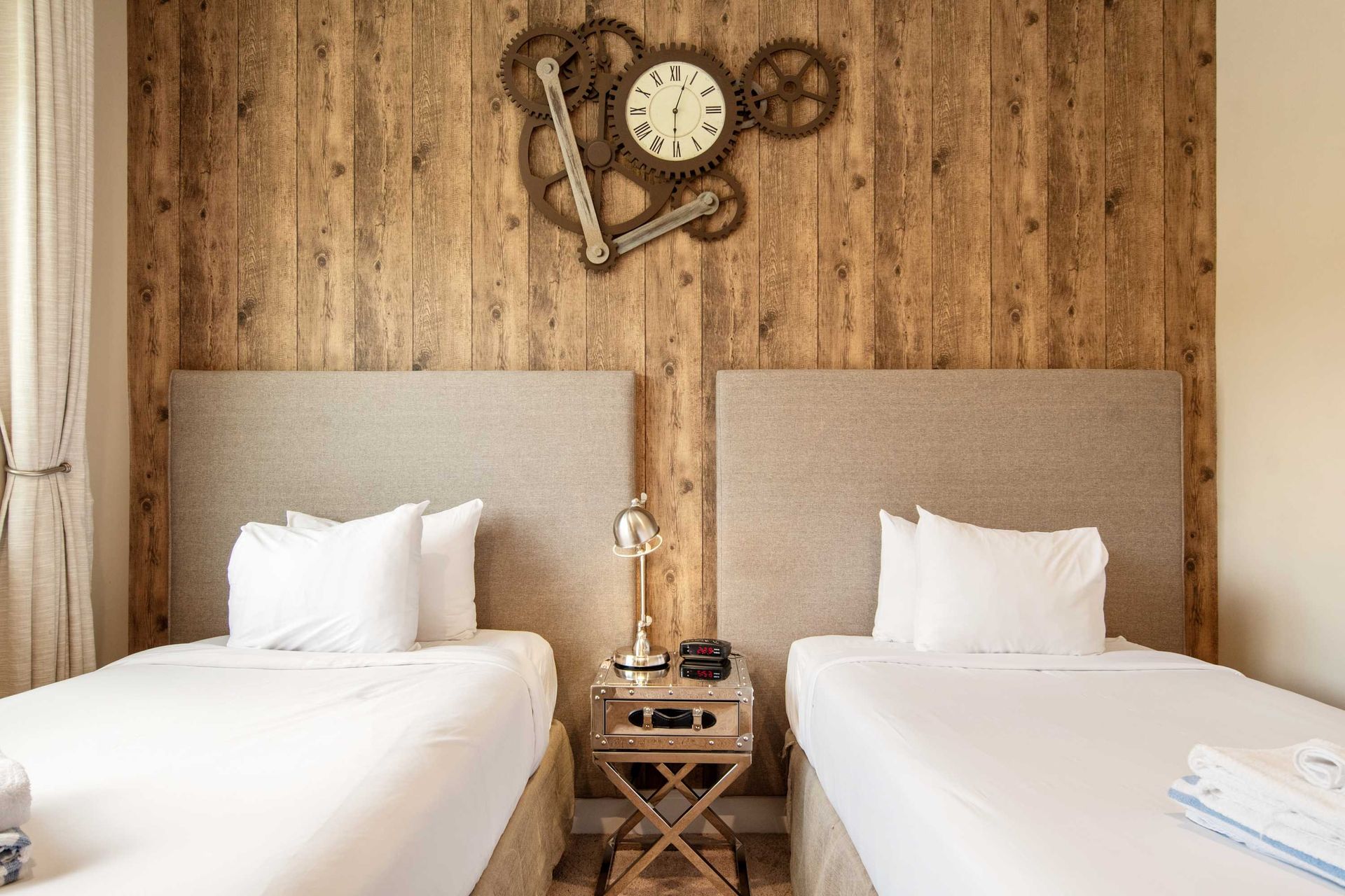 Twin beds and rustic wood wall with a cool gear-themed clock.