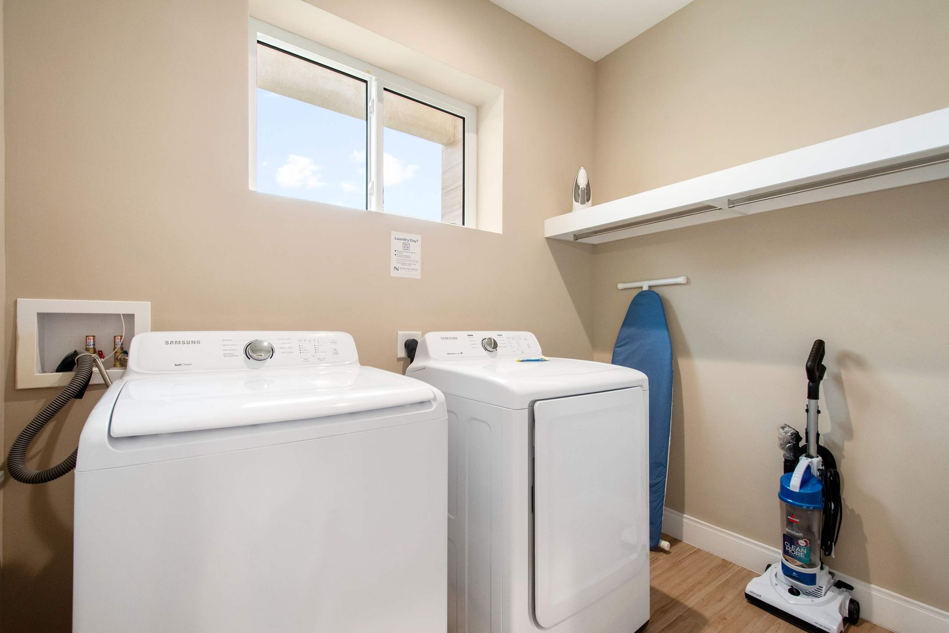 In-unit laundry room with full-size washer, dryer, and storage shelf.