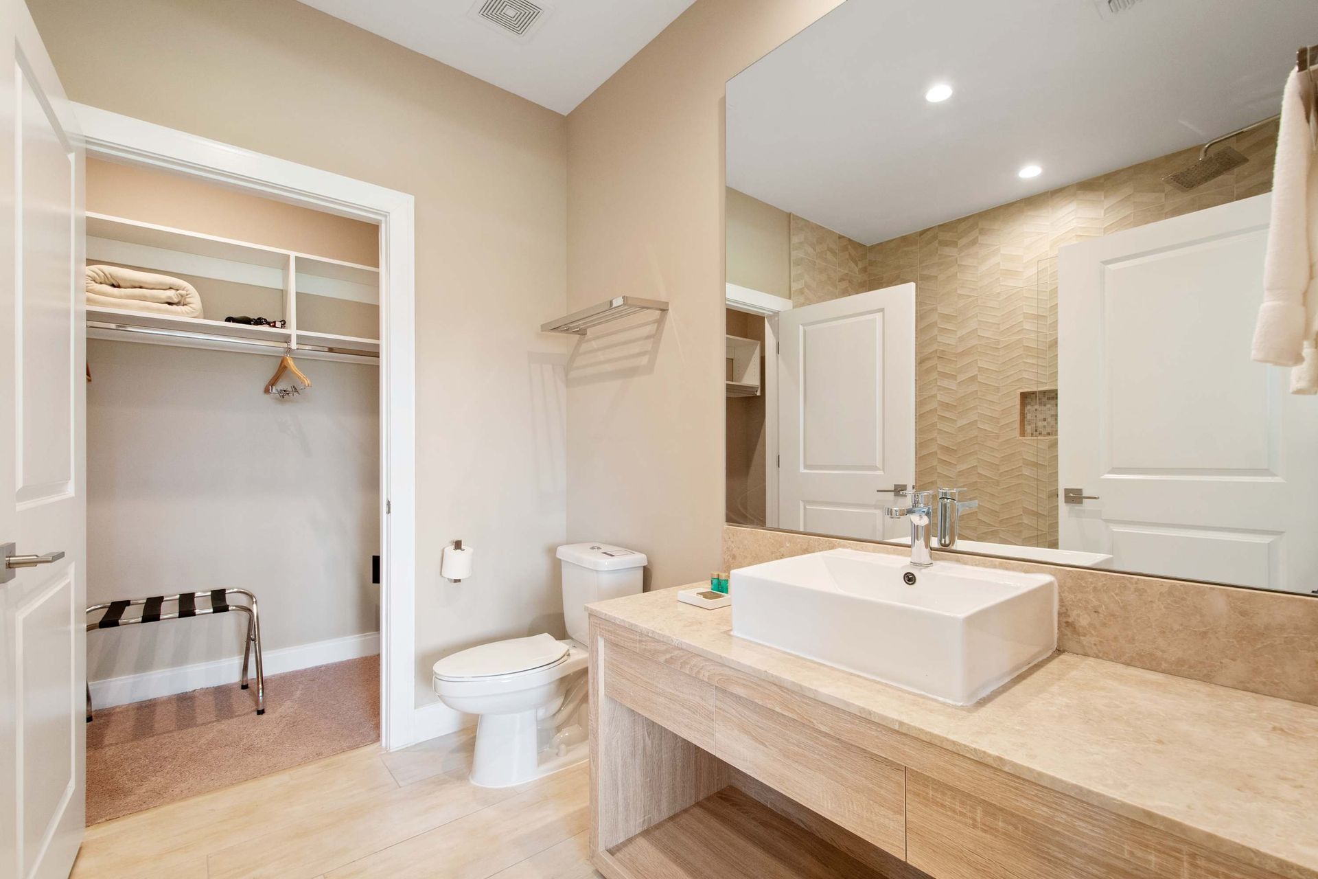 Stylish floating vanity, vessel sink, and walk-in closet for easy storage.