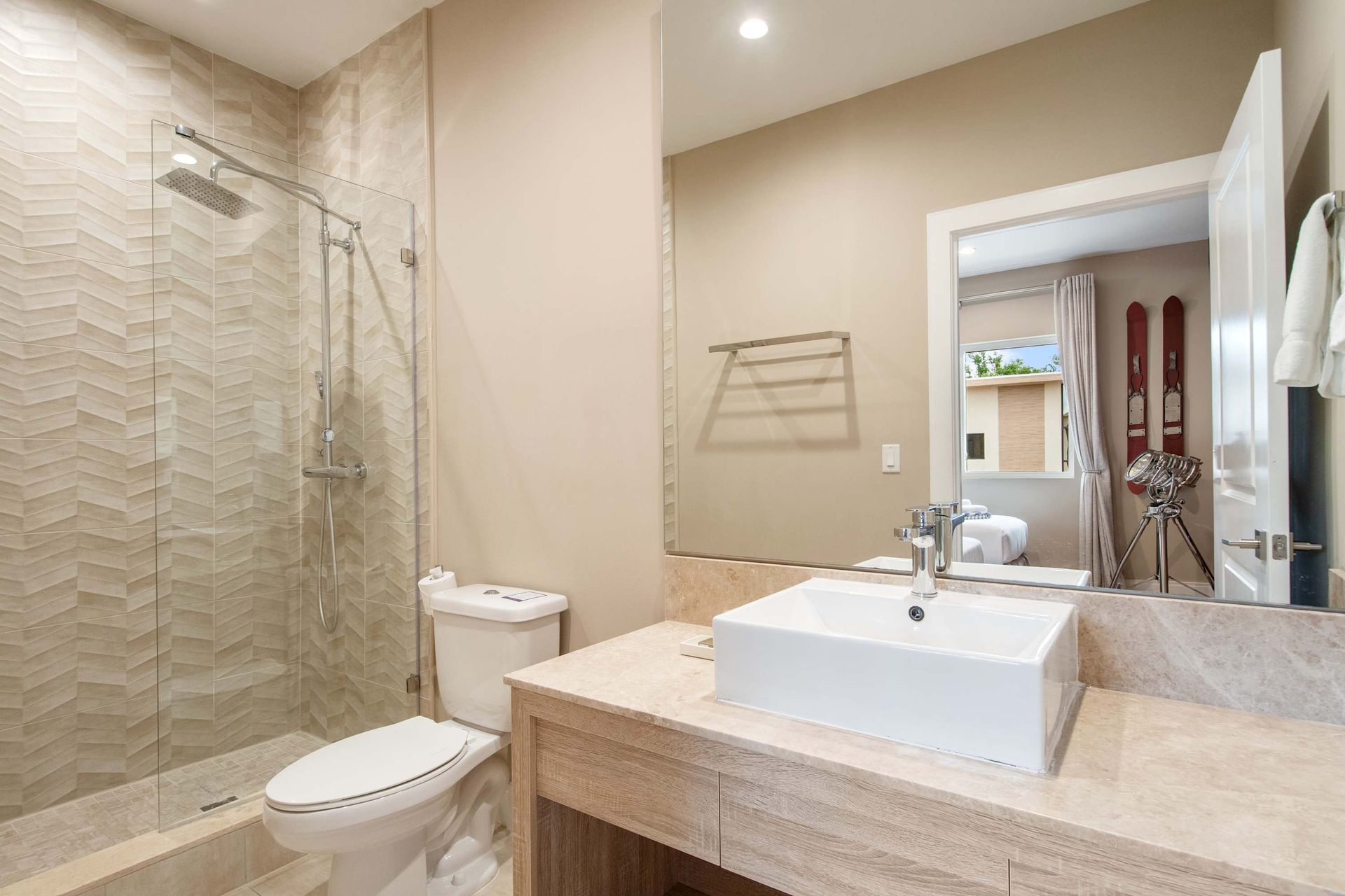 Modern bath with vessel sink, walk-in shower, and textured tile.