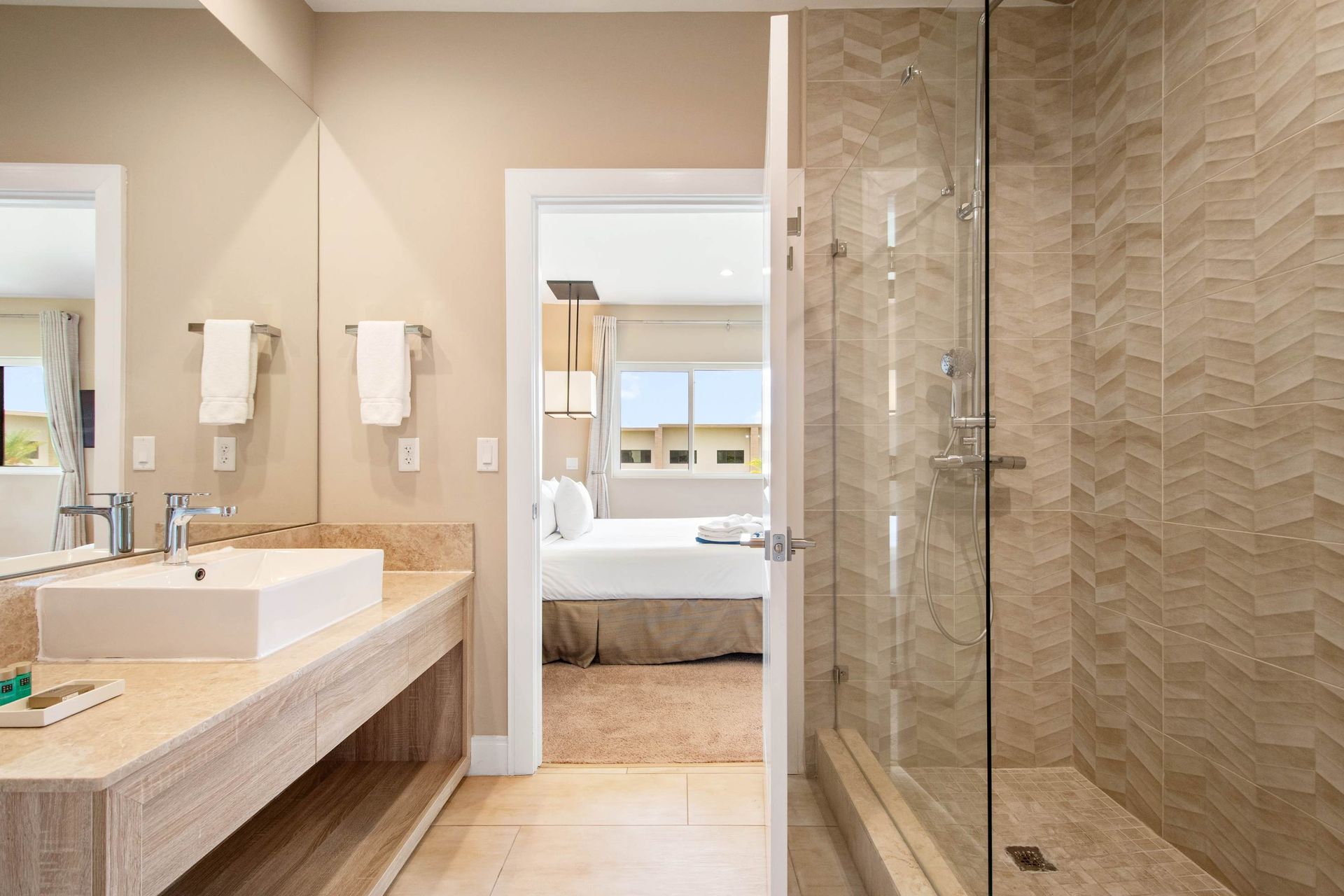 Modern bath: glass walk-in shower, vessel sink, and bedroom view.