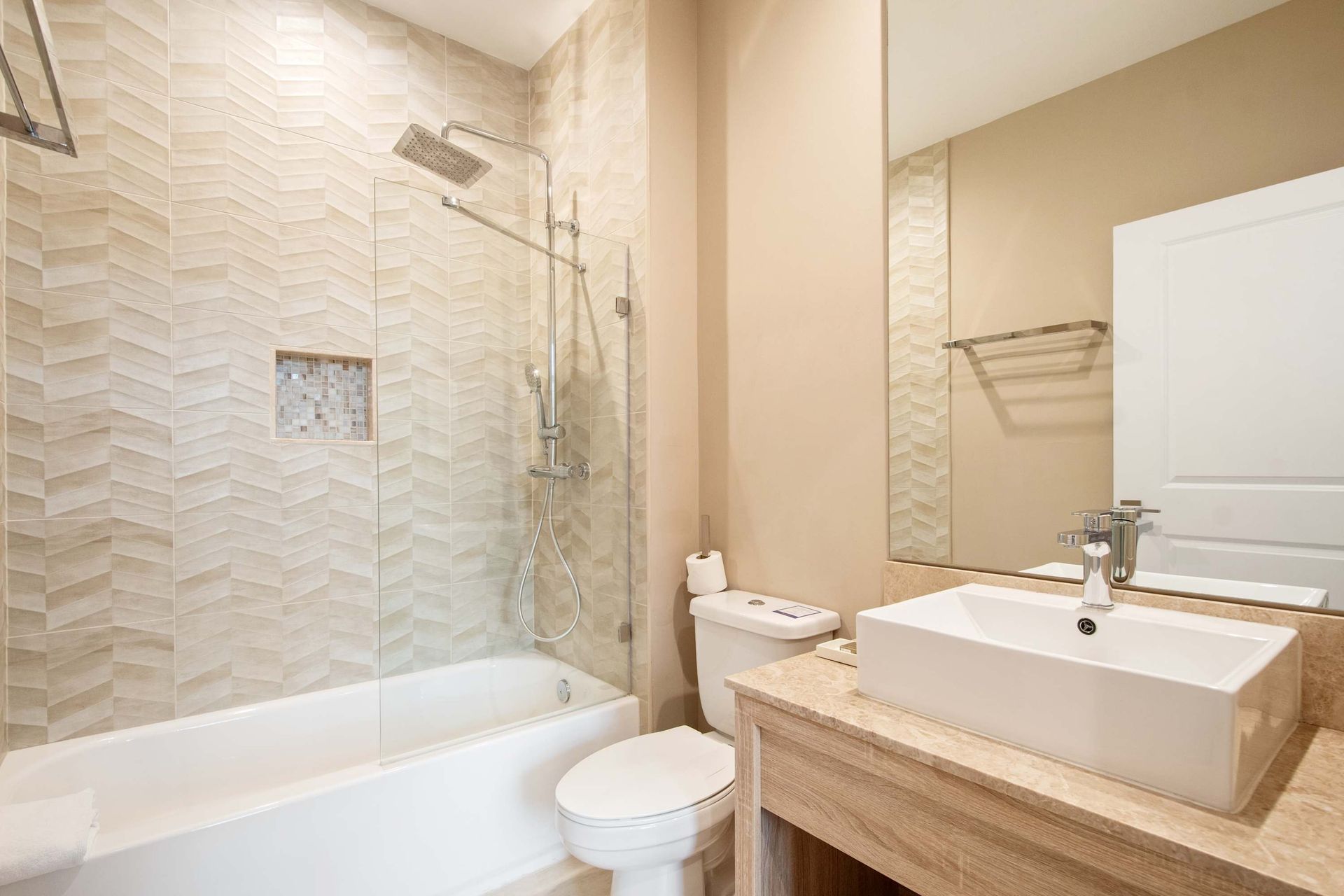 Modern bath: vessel sink, herringbone tile, and glass shower.
