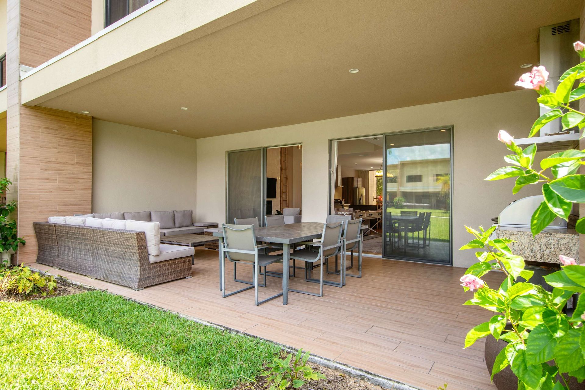 Covered patio with full outdoor dining, lounge seating, and grill area.