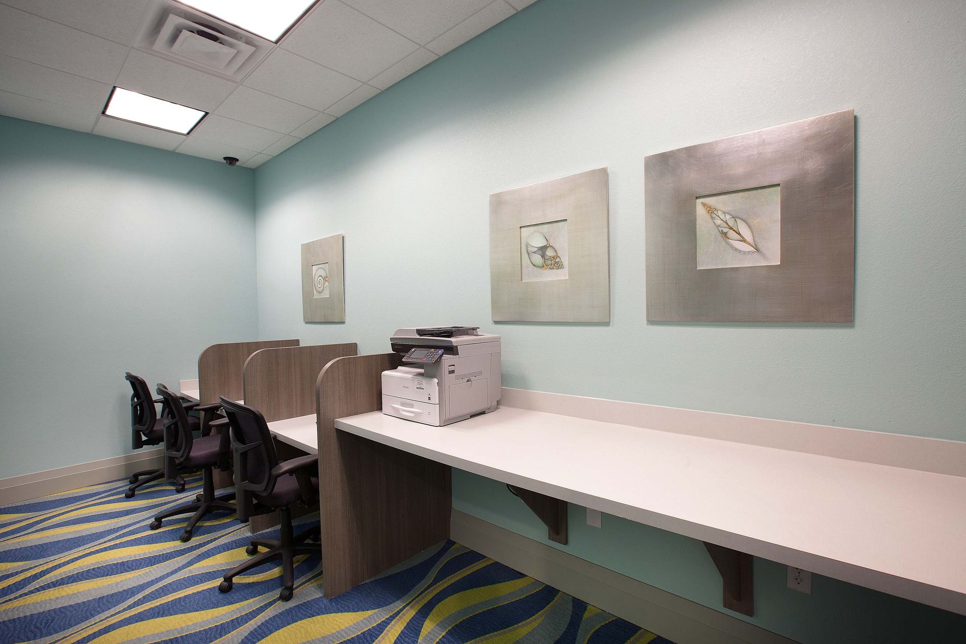 Dedicated business center with desks, chairs, and printer access.