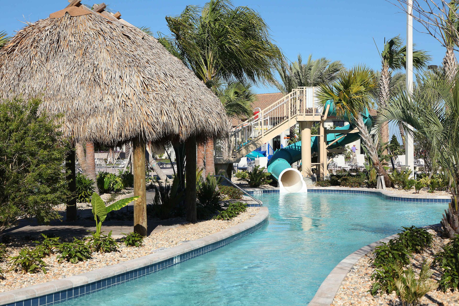 Lazy river fun! Tiki hut, water slide, and tropical landscaping.