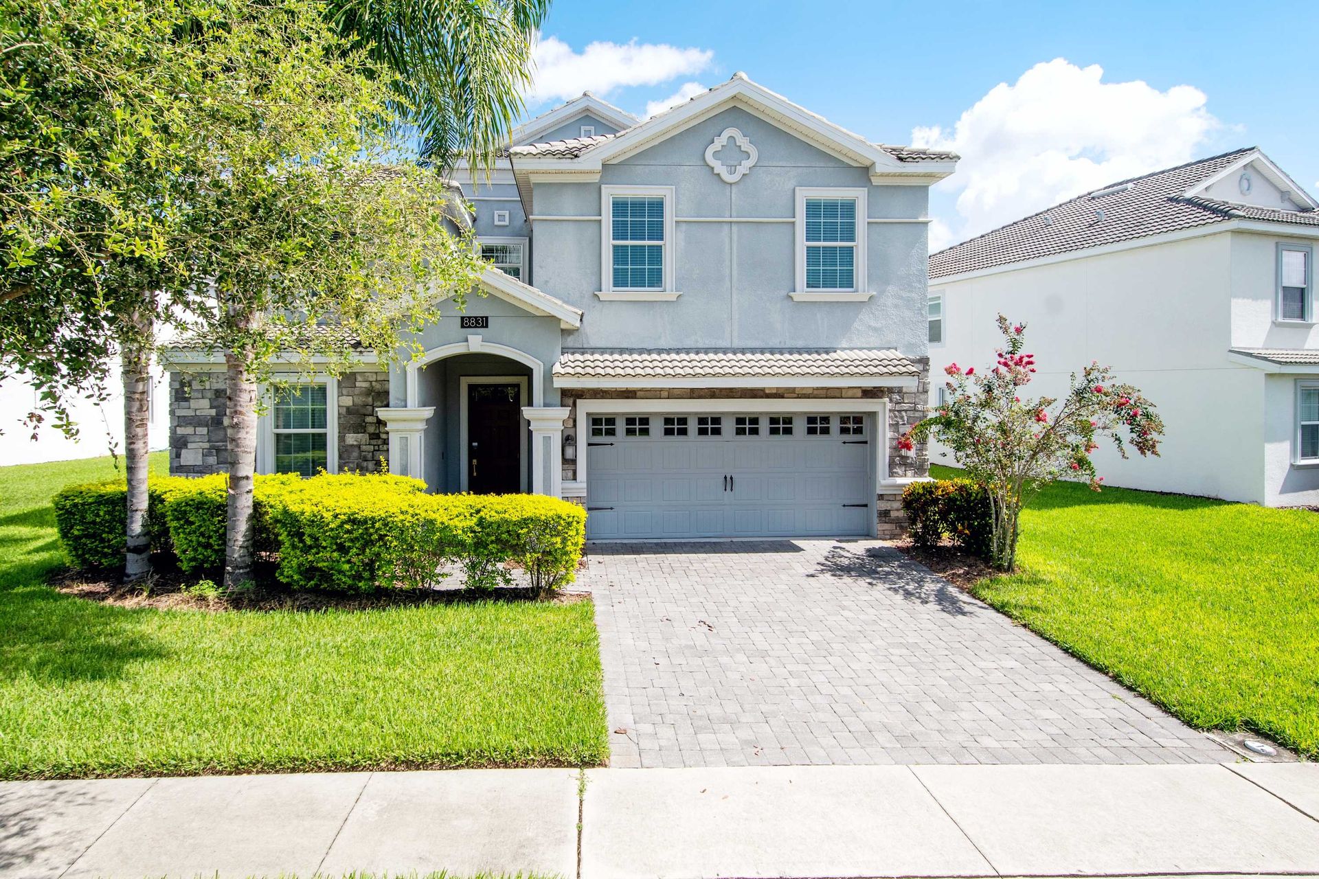 Stunning gray home with a tile roof and two-car garage.