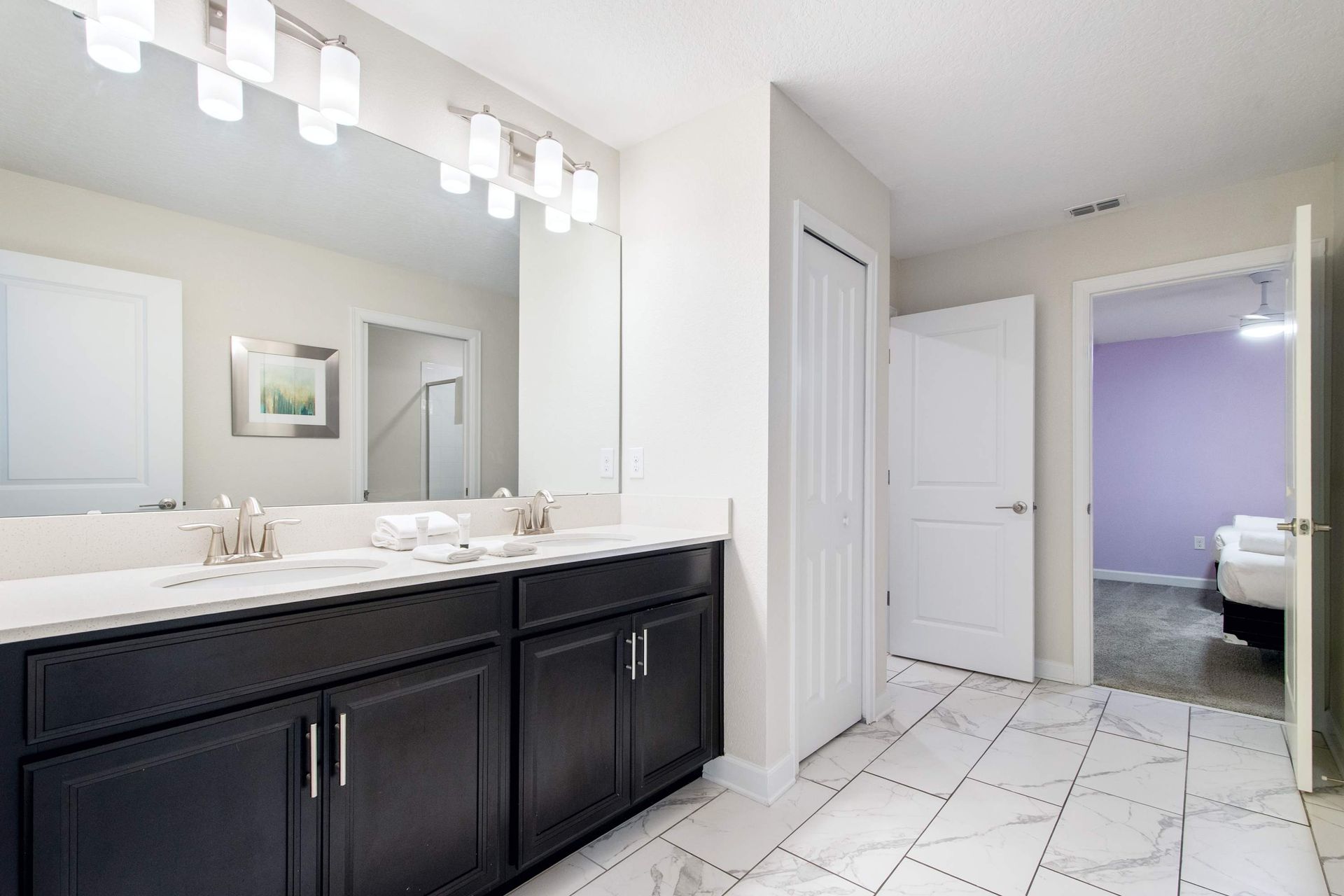 Bright, clean, and modern bath with large mirror and dual sinks.