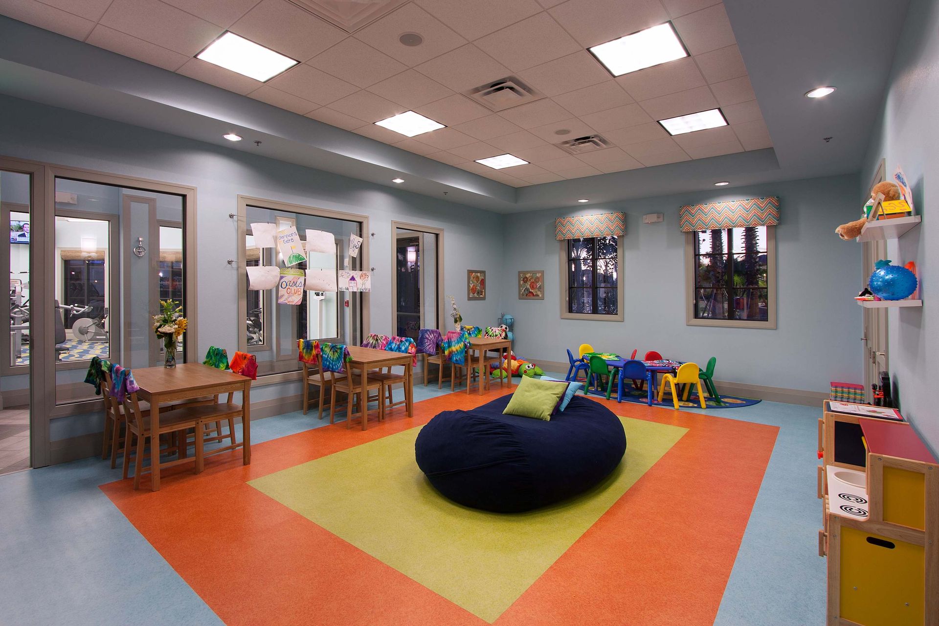 Indoor kids' club with tables, chairs, toys, and a large blue bean bag.