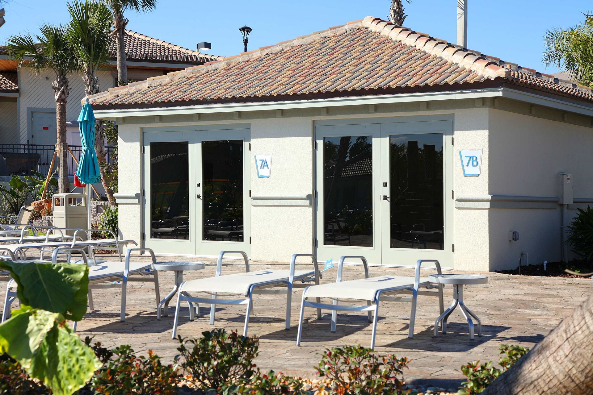 Sunny Florida-style building with light stucco, palm trees, and bright white furniture.