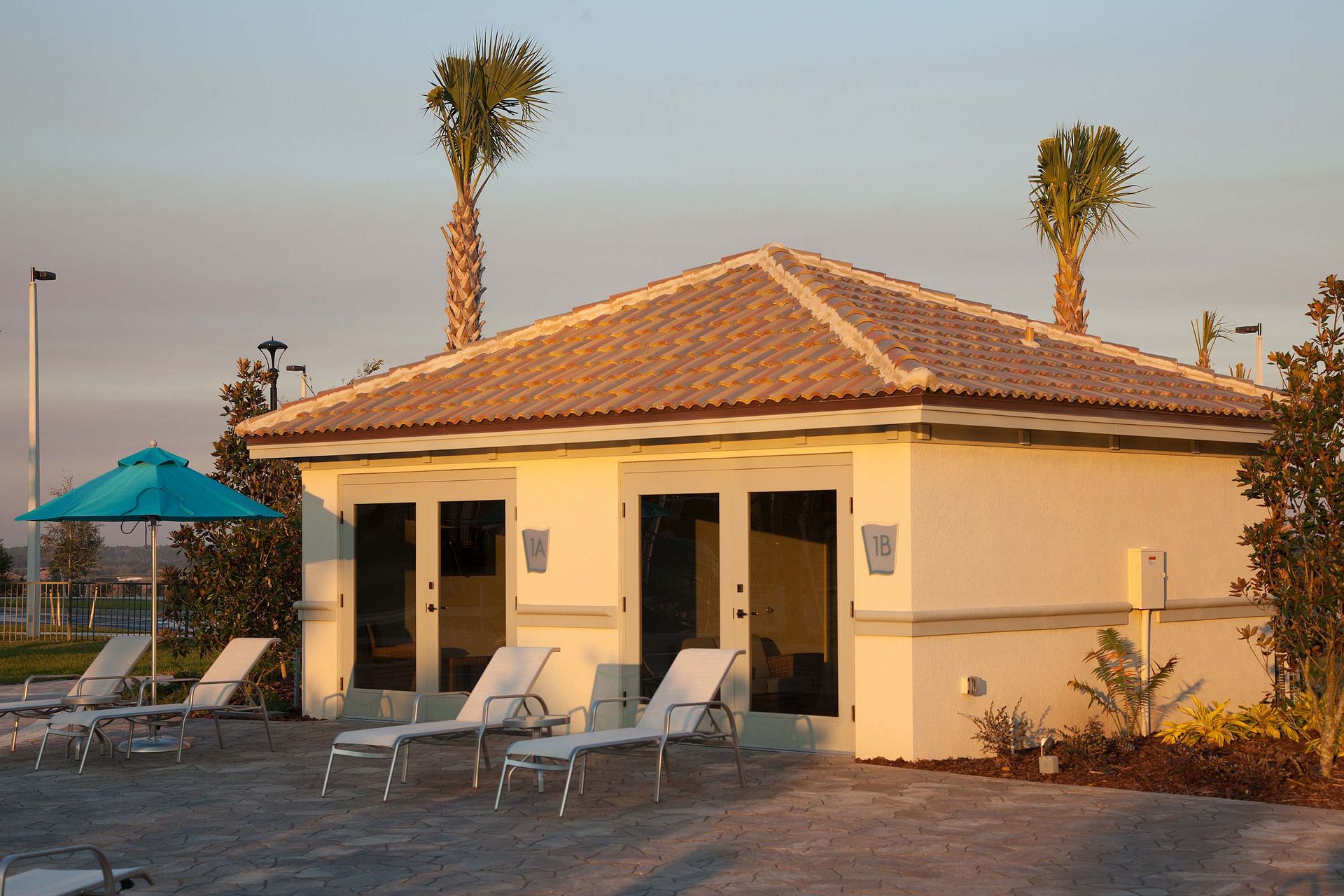 Warm golden hour light on a single-story building with a tile roof and deck.