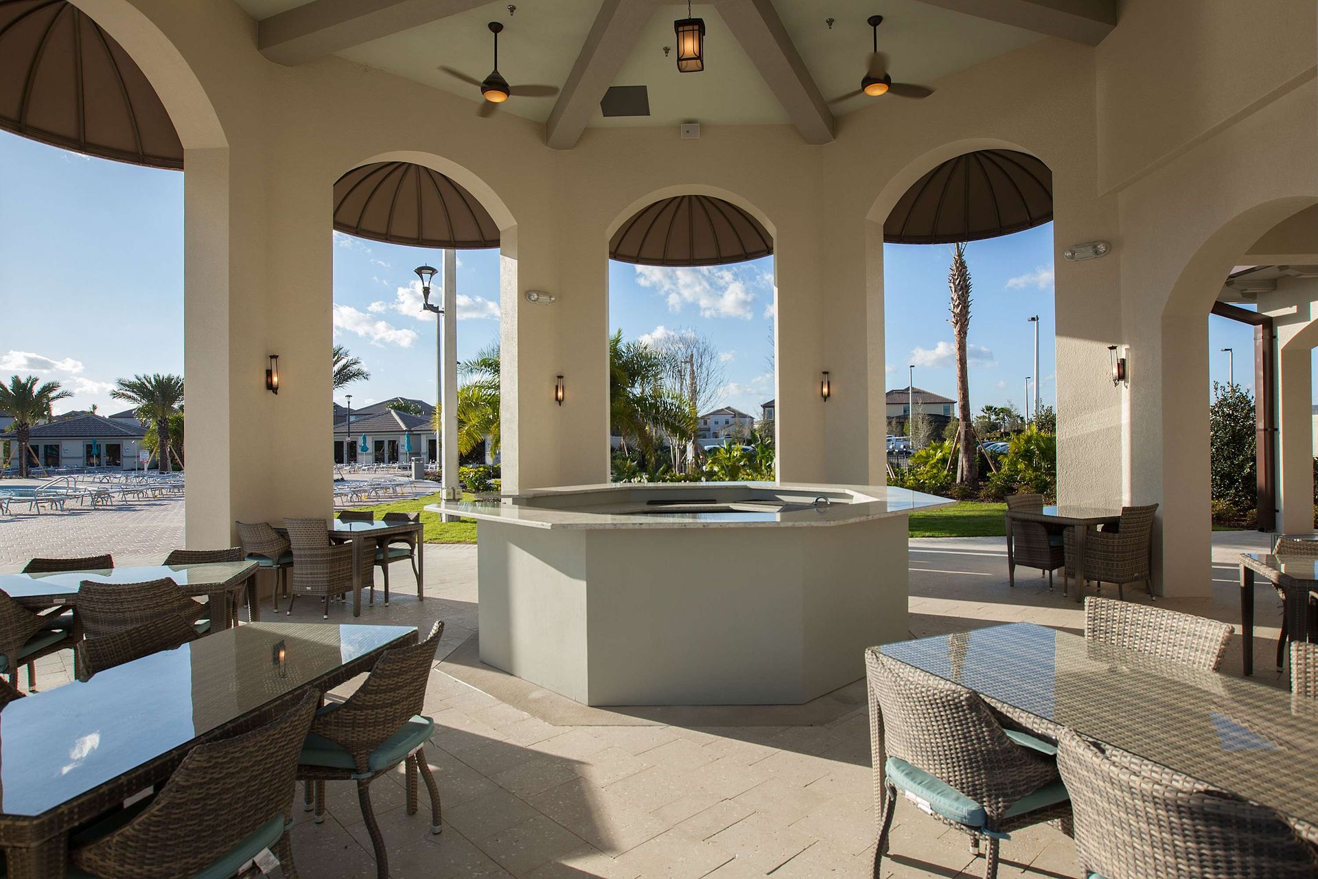 Outdoor community pavilion with a large circular bar, dining tables, and seating.