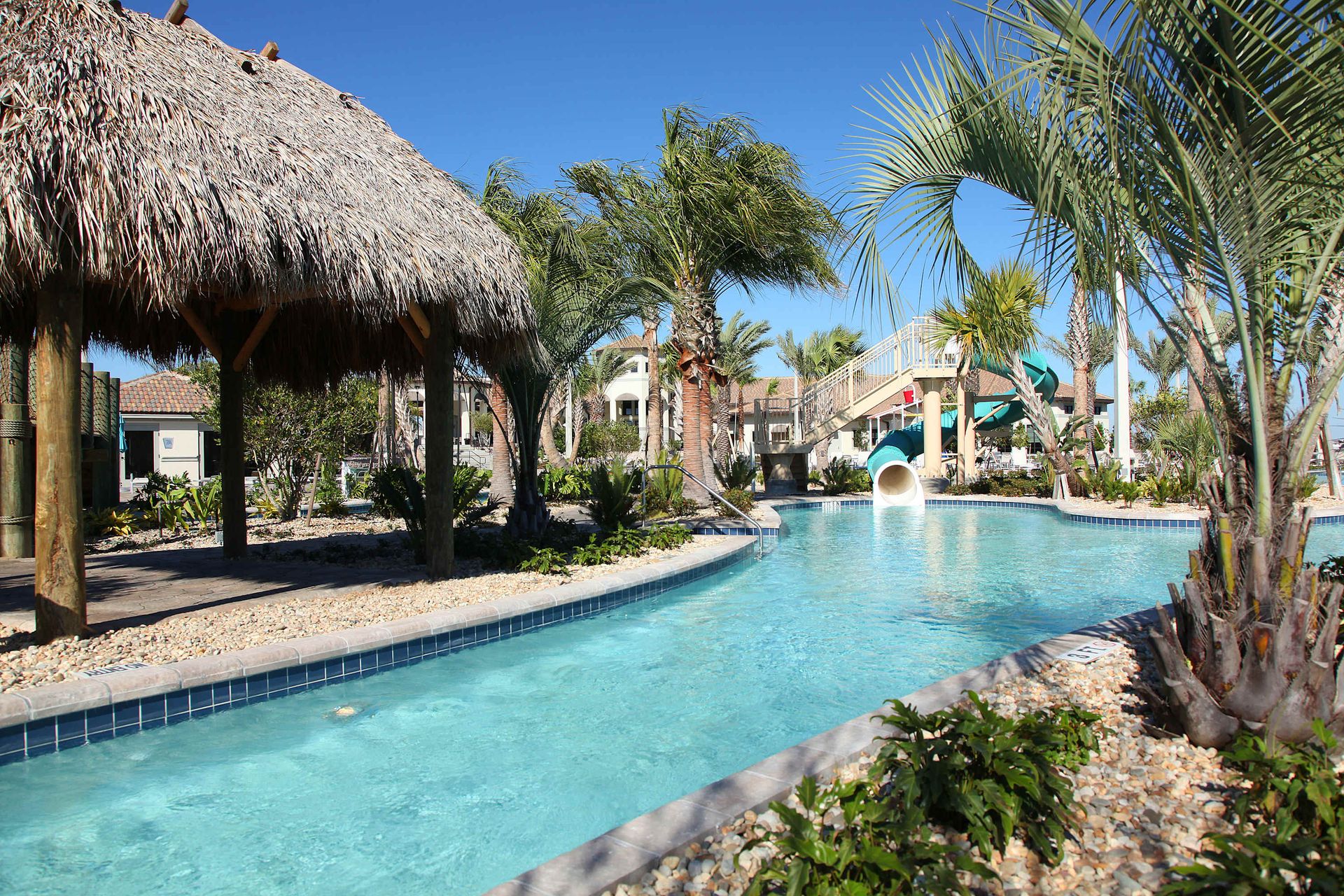 Sun deck and lazy river with a wooden bridge at a water park.