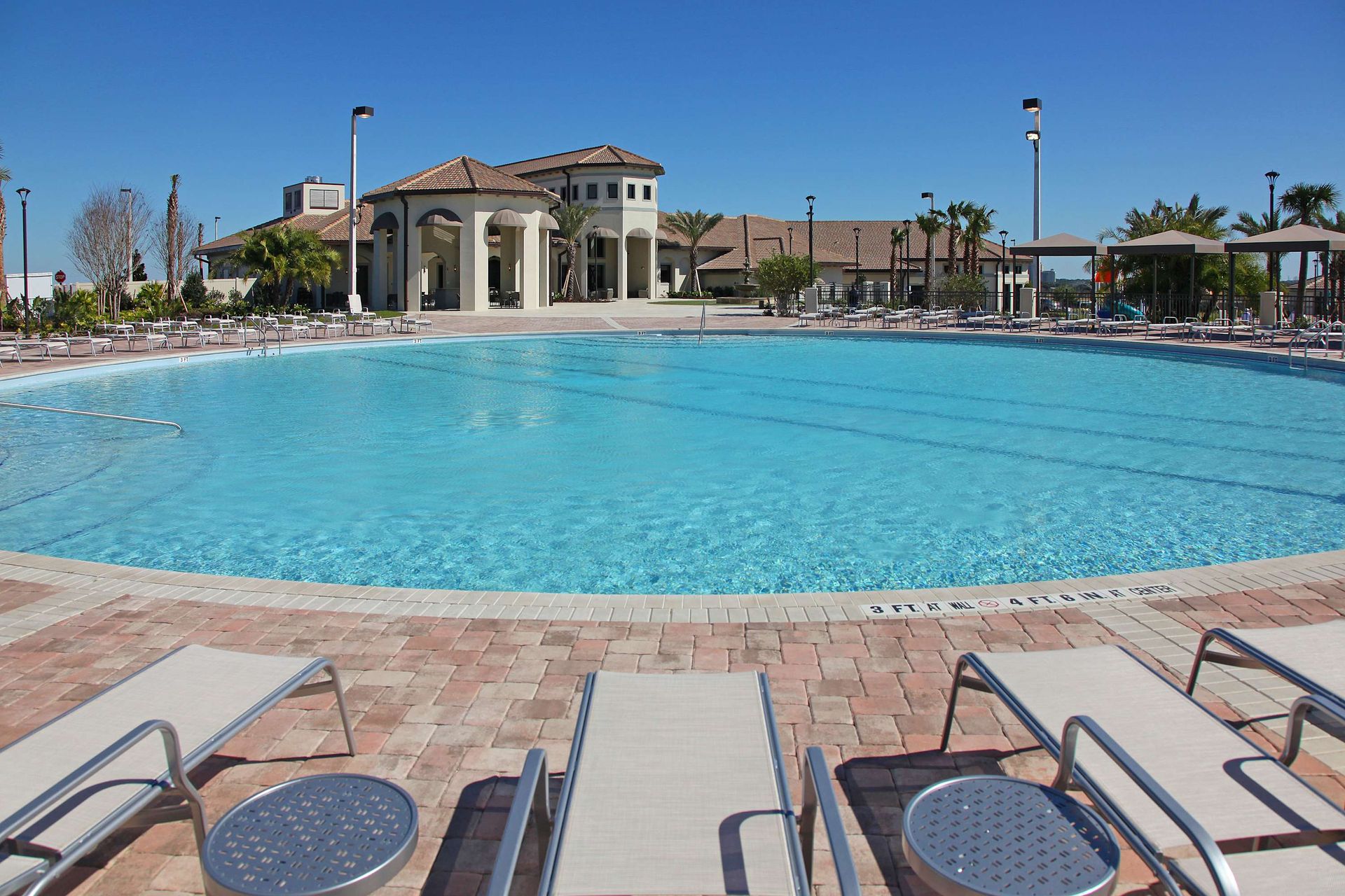 Large resort pool, sun deck with lounge chairs, and a clubhouse in the background.