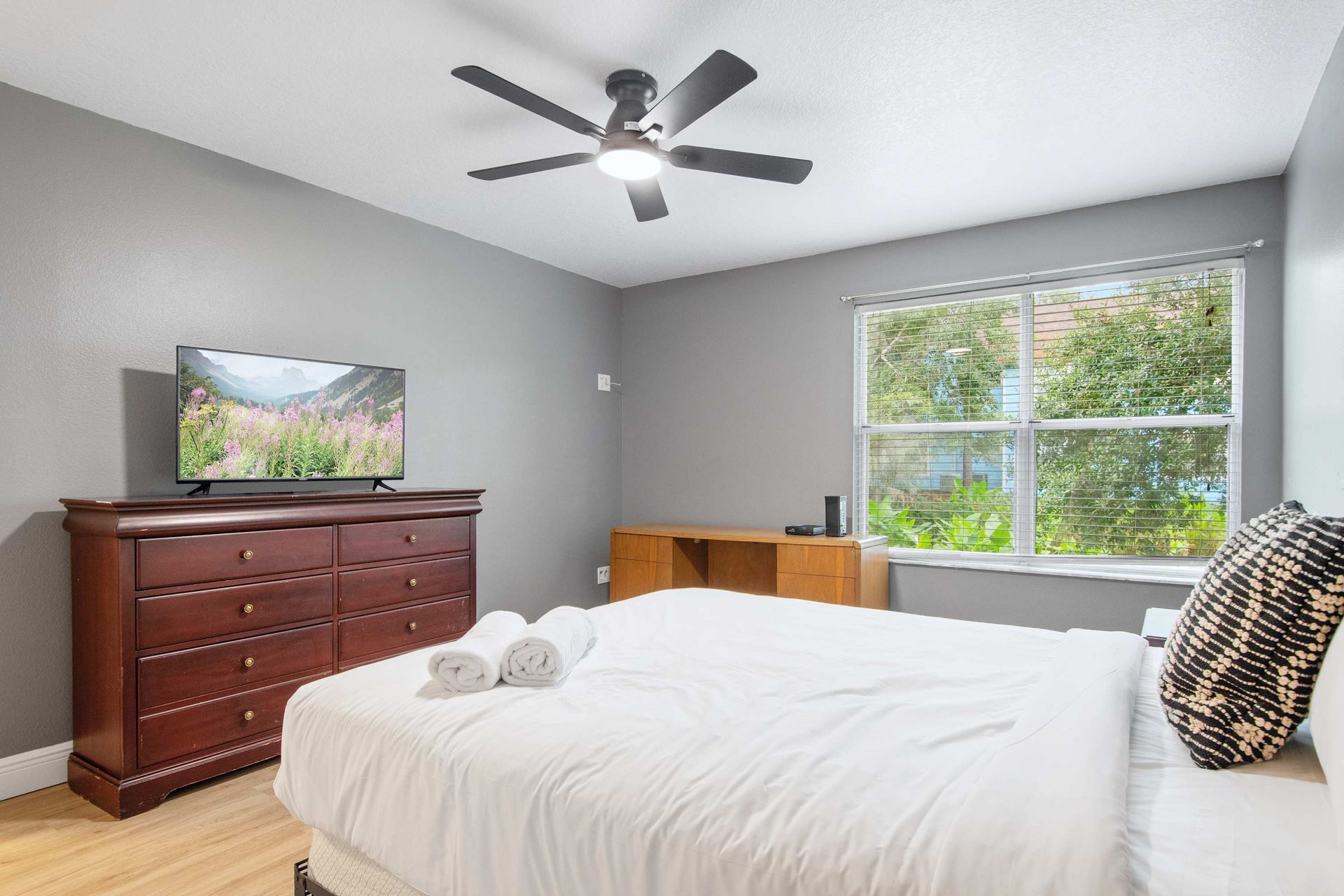 Cozy queen bed, TV, and work space with a bright view.