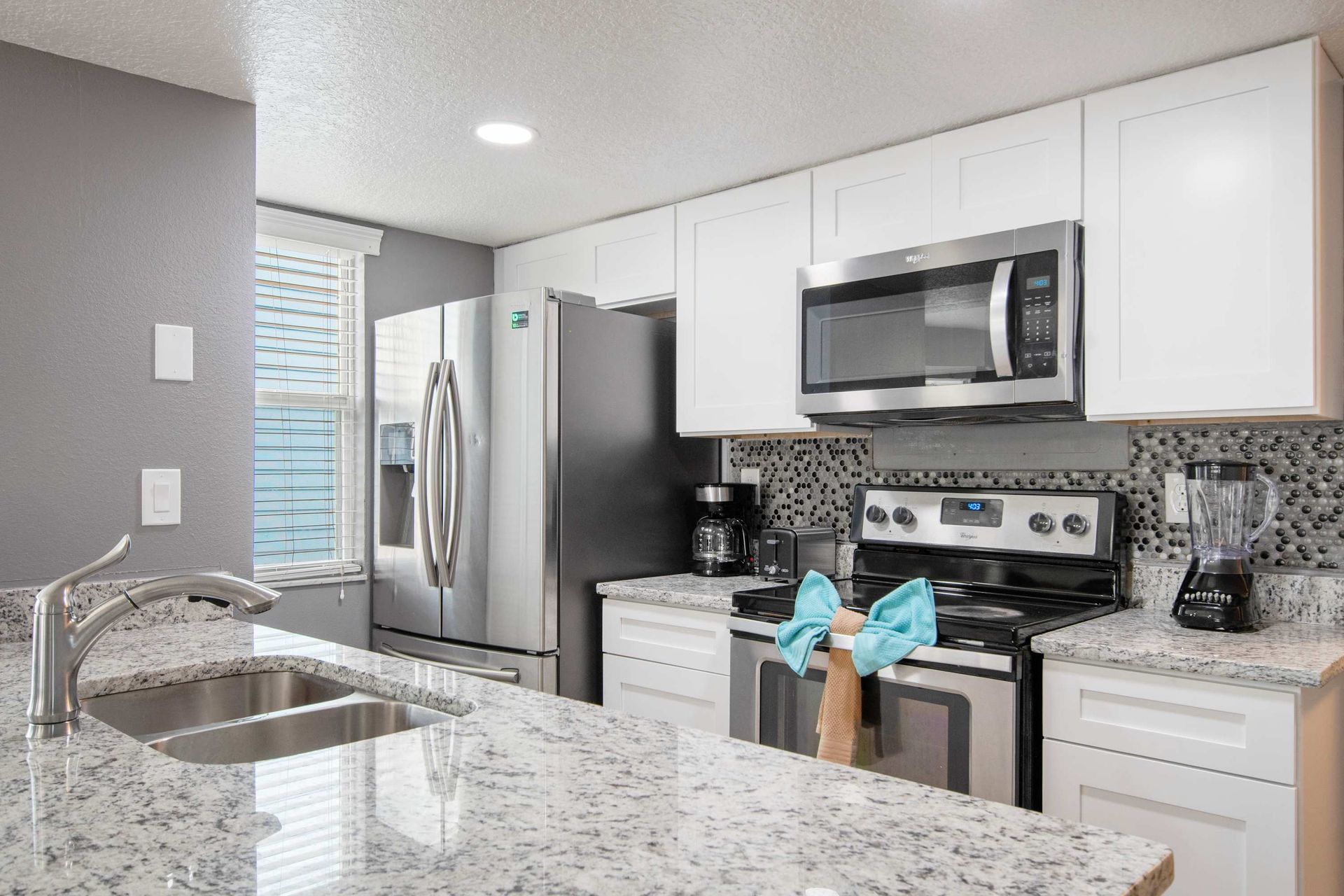 Sleek white cabinets, granite counters, and stainless steel appliances.