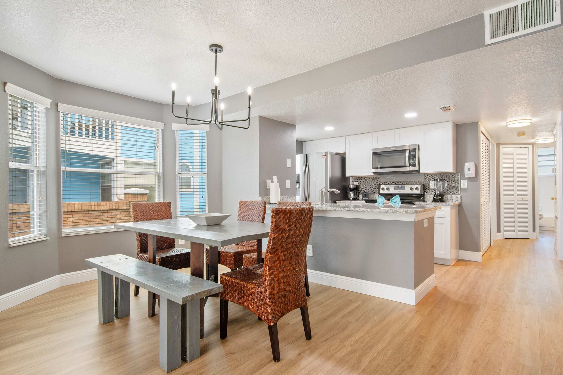 Coastal gray and white kitchen and dining area with wicker accents.