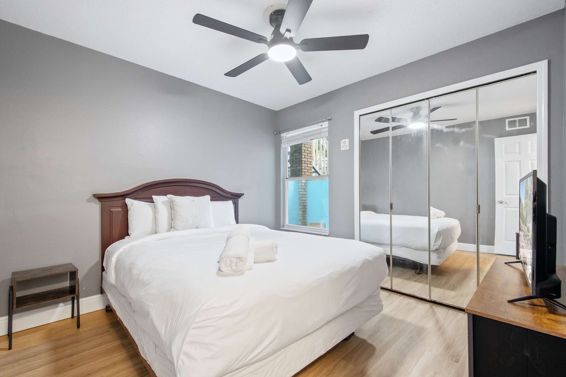 Cozy queen bed, sleek gray walls, and mirrored closet for extra light. 
