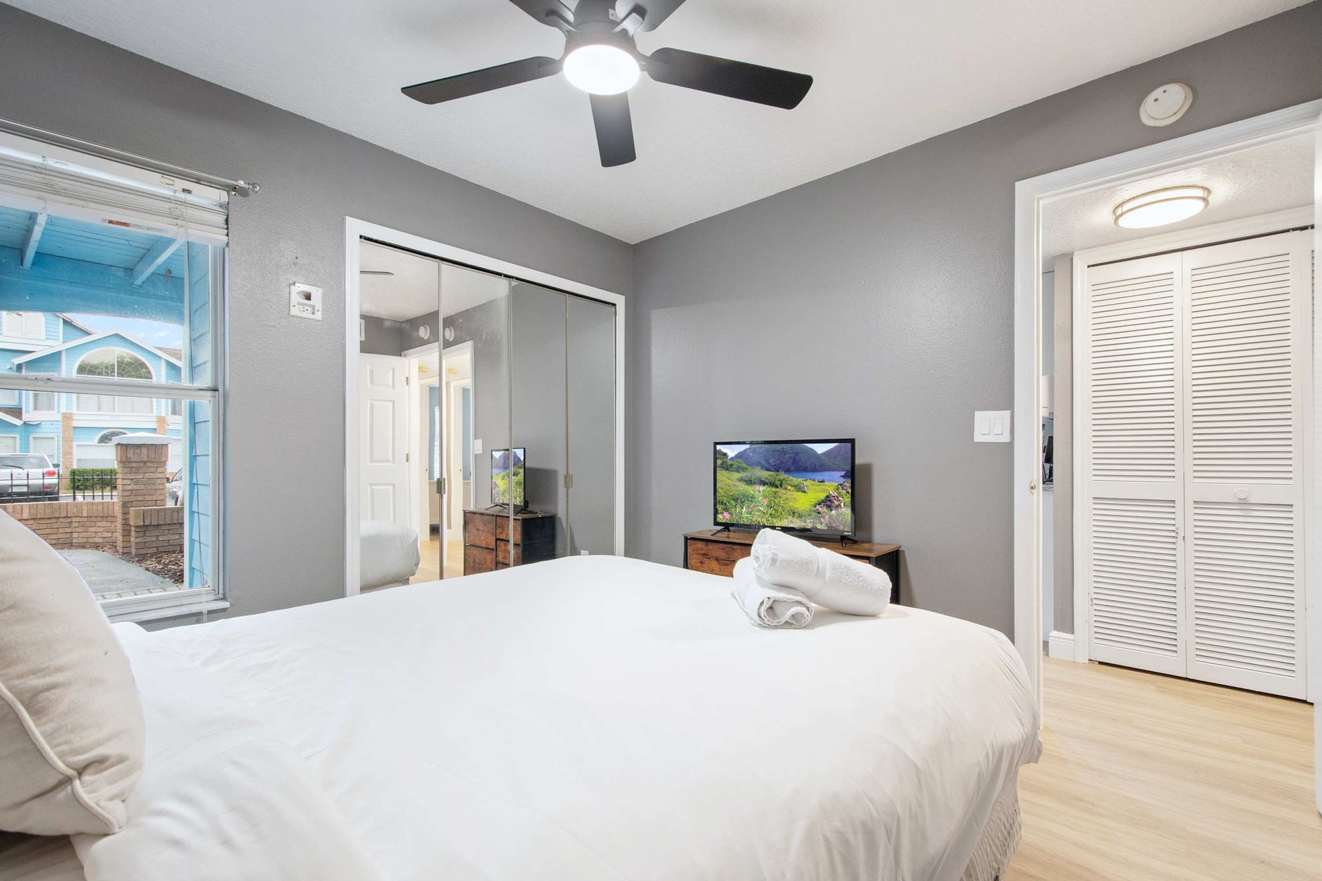 Cozy queen bed, TV, and mirrored closet in a chic gray room. 