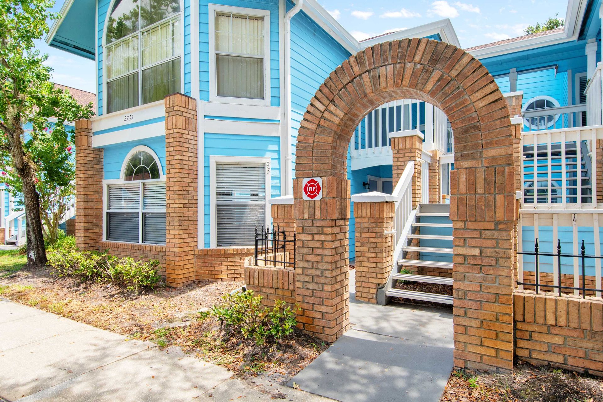 Brick arch leads up to the bright blue, stylish entry.