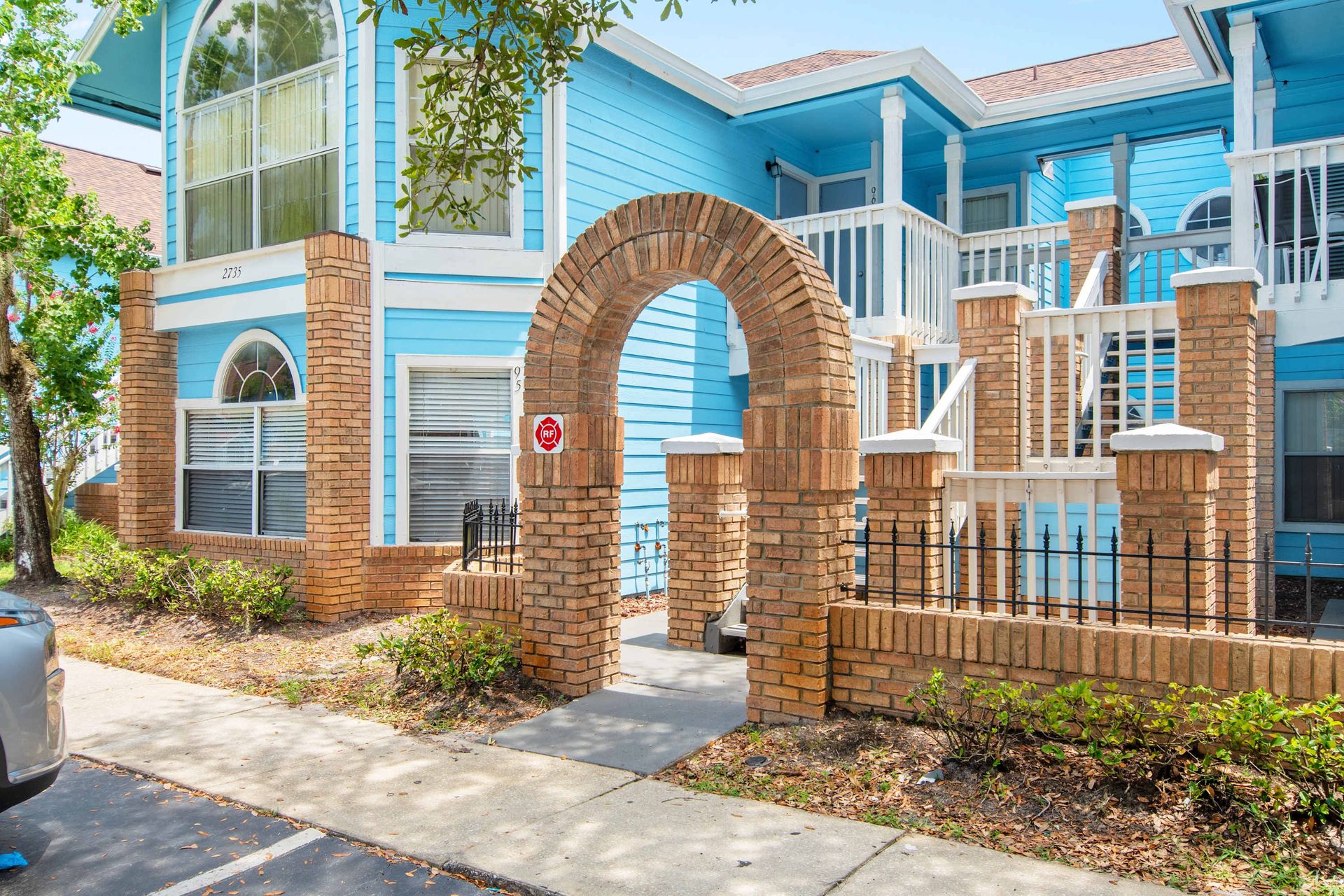 Bright blue townhome facade with a welcoming brick arch. 