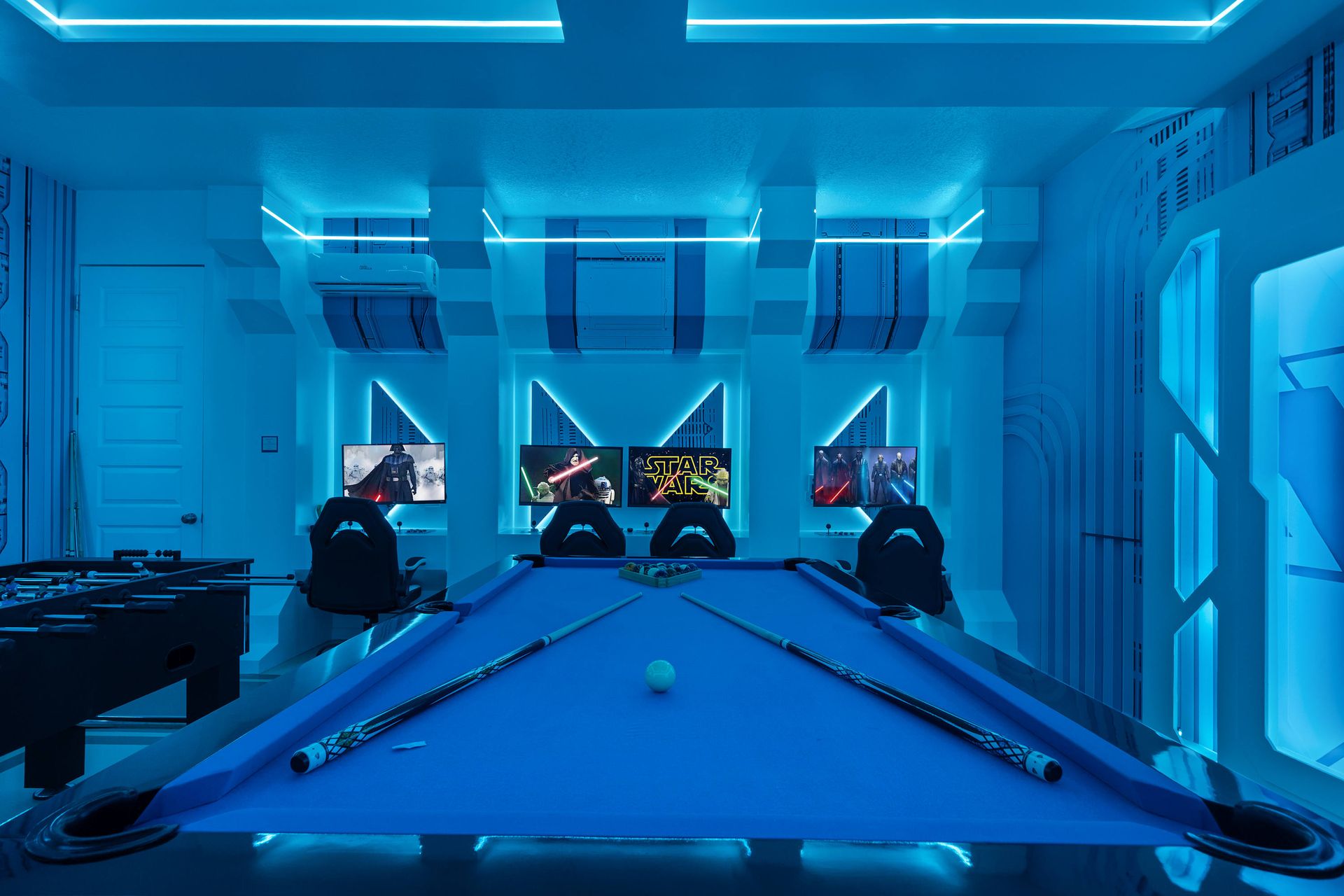 Blue-lit modern game lounge with pool and multiple screens.