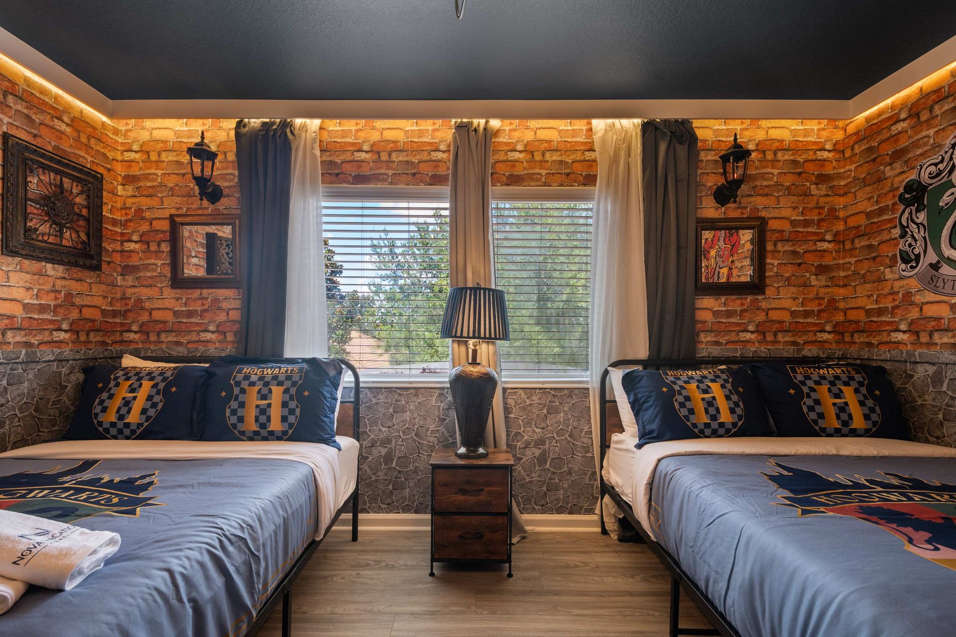 Twin beds in a brick-walled room with a magical school theme. 