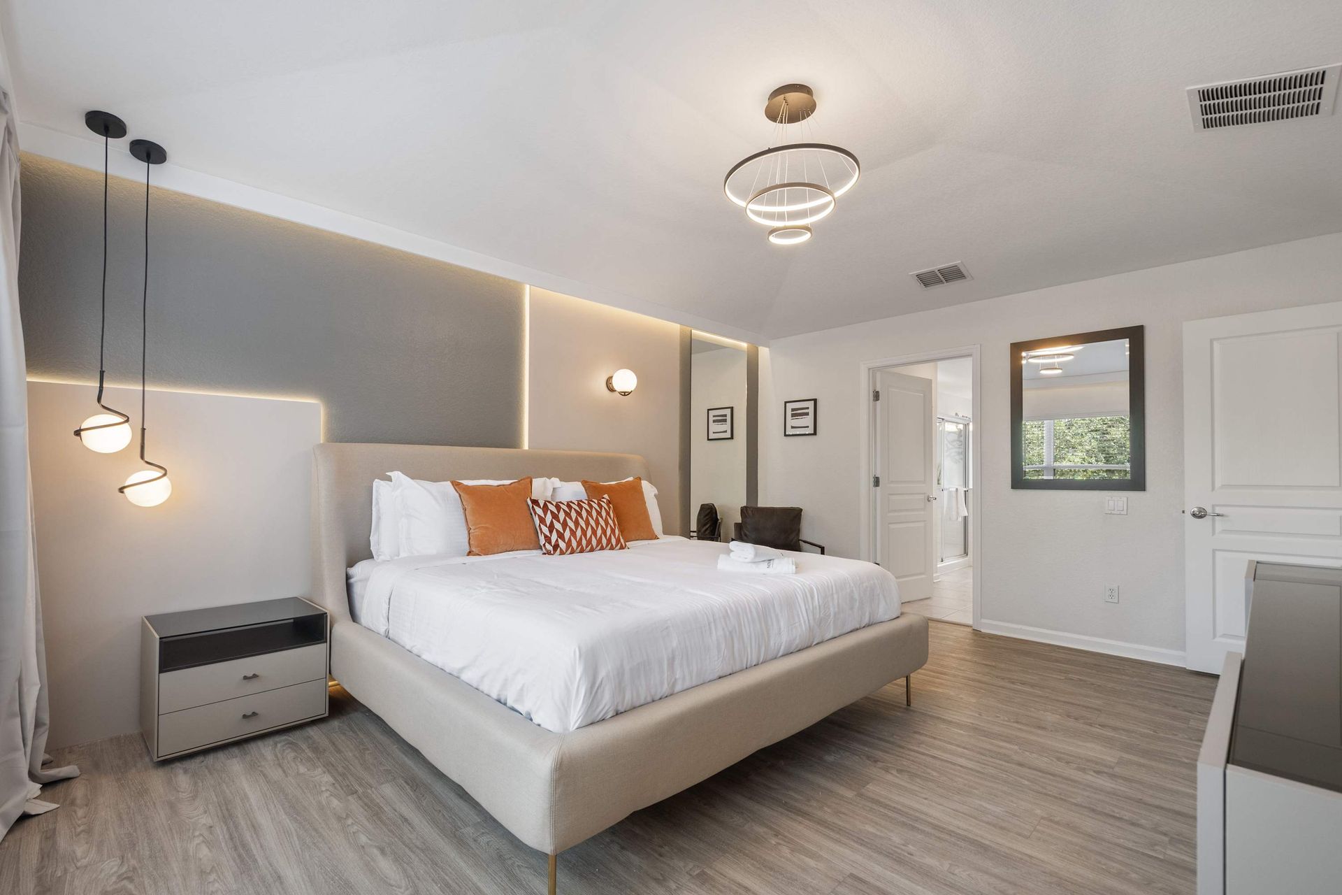 Luxurious king bed, modern lighting, and chic orange accents.