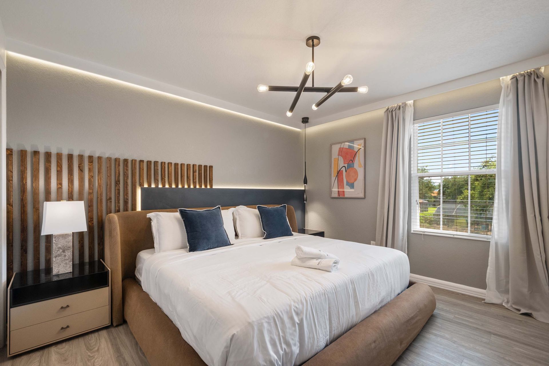 Custom headboard, ambient lighting, and modern chandelier define this suite.