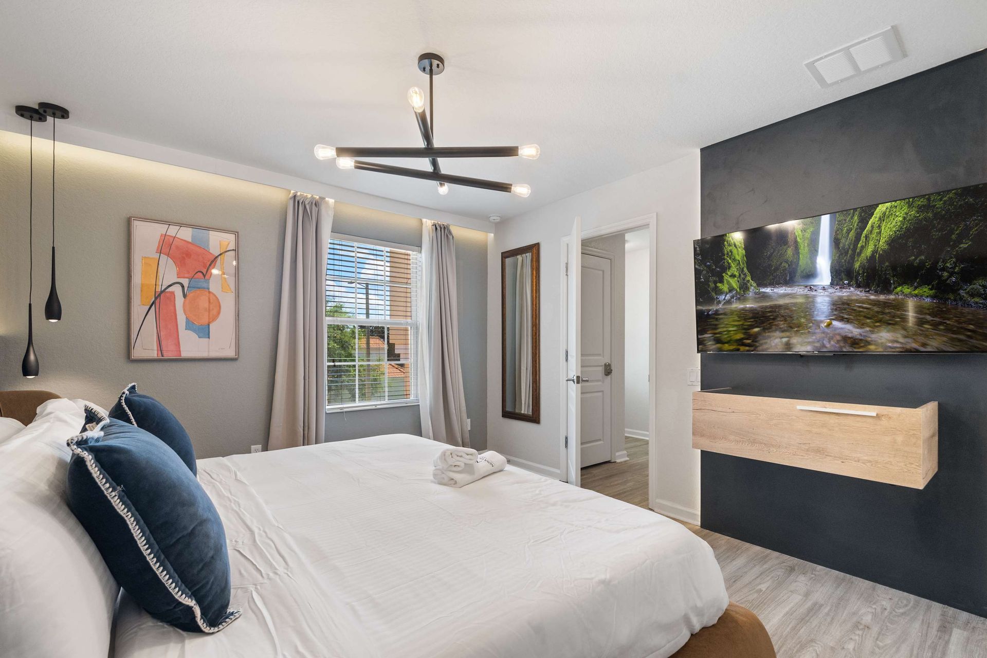 Modern king suite with custom TV wall and designer lighting.