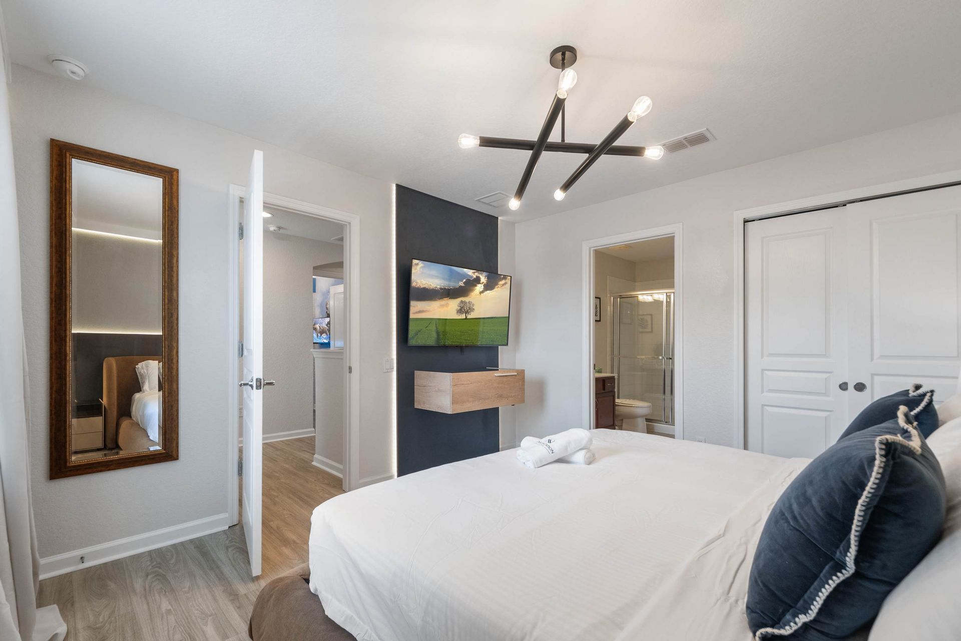 Sleek suite with a minimalist TV wall, modern chandelier, and mirror.