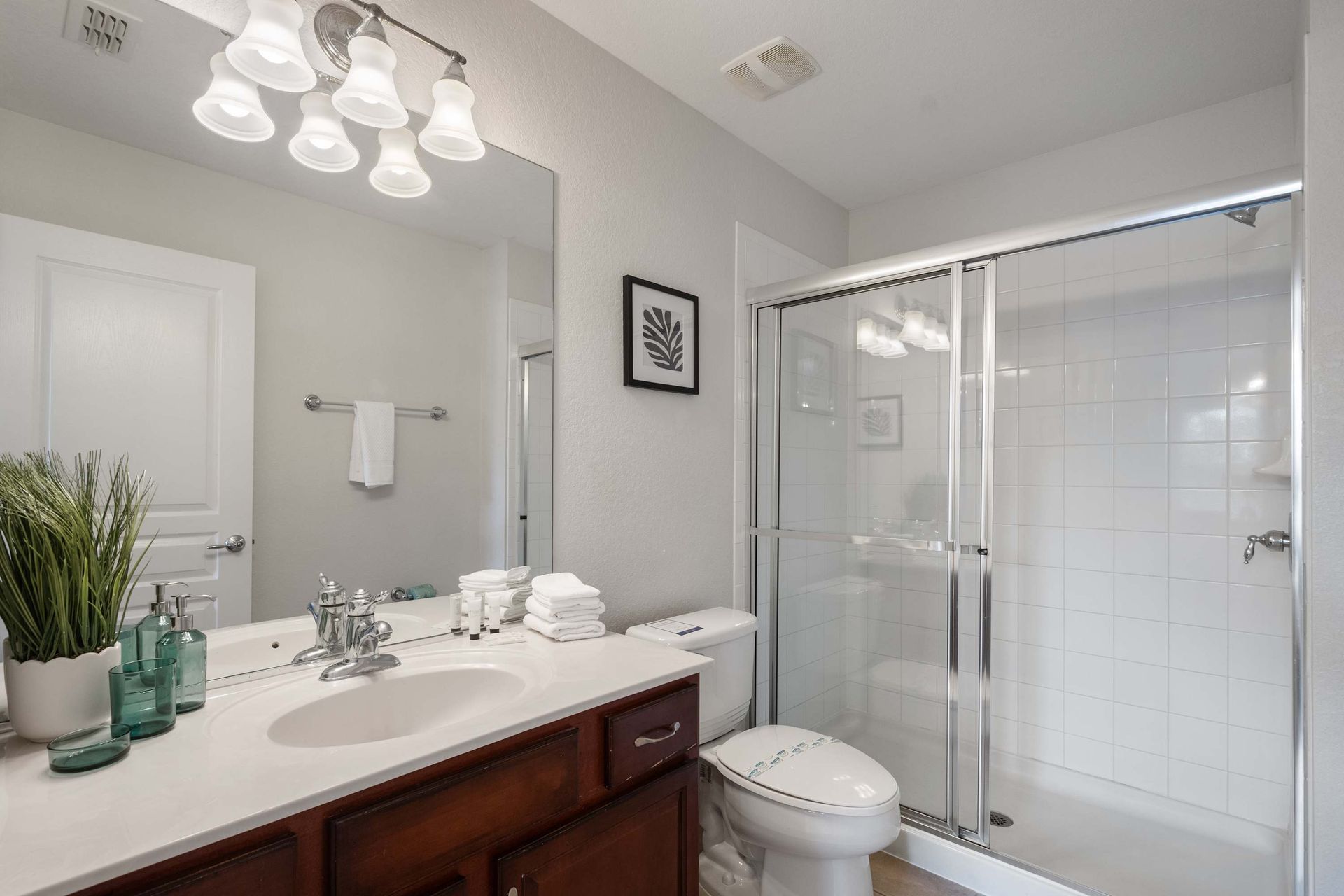 Clean and bright bathroom with a walk-in glass shower and dark vanity.