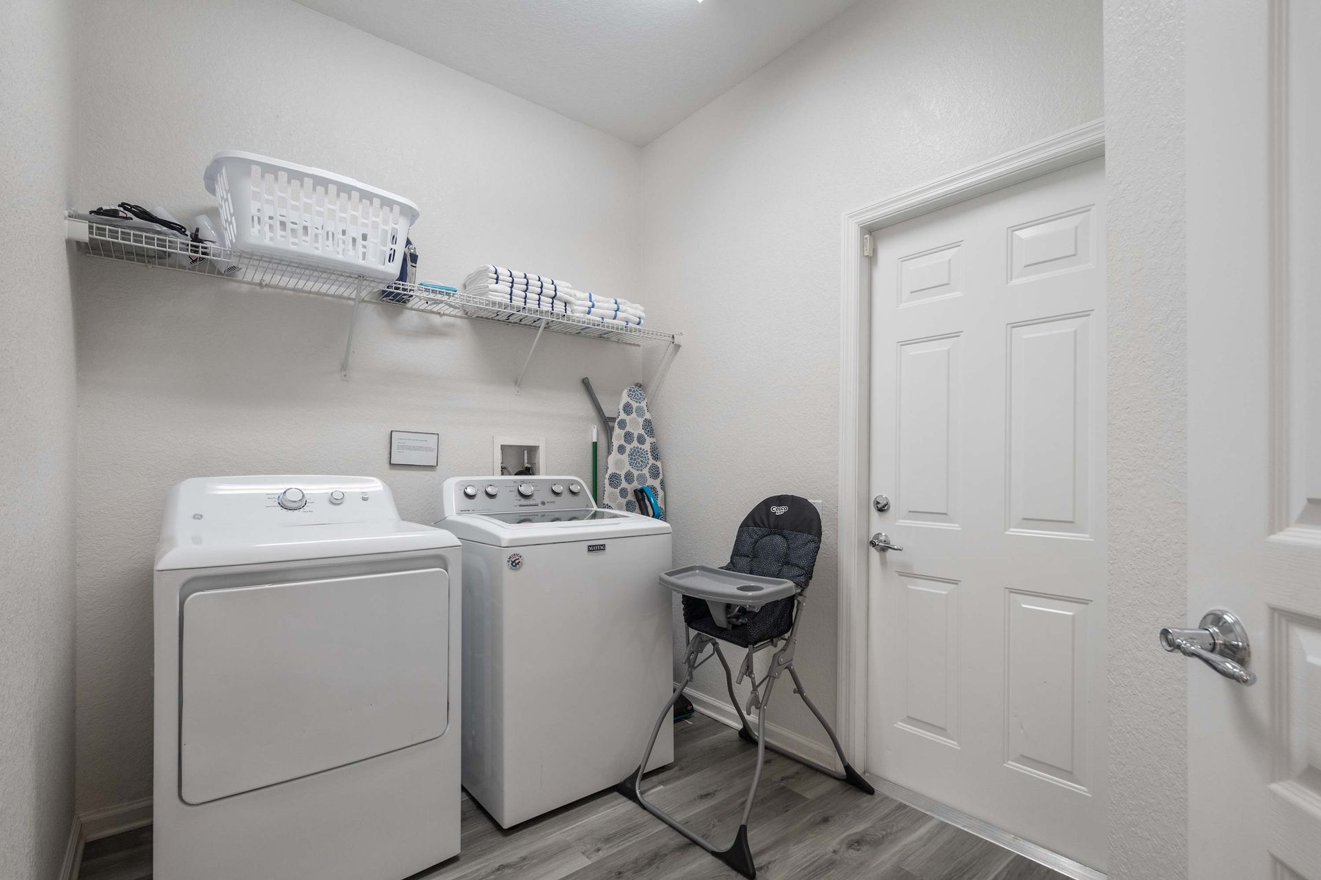 In-unit laundry room with full-size washer, dryer, and storage shelves. 