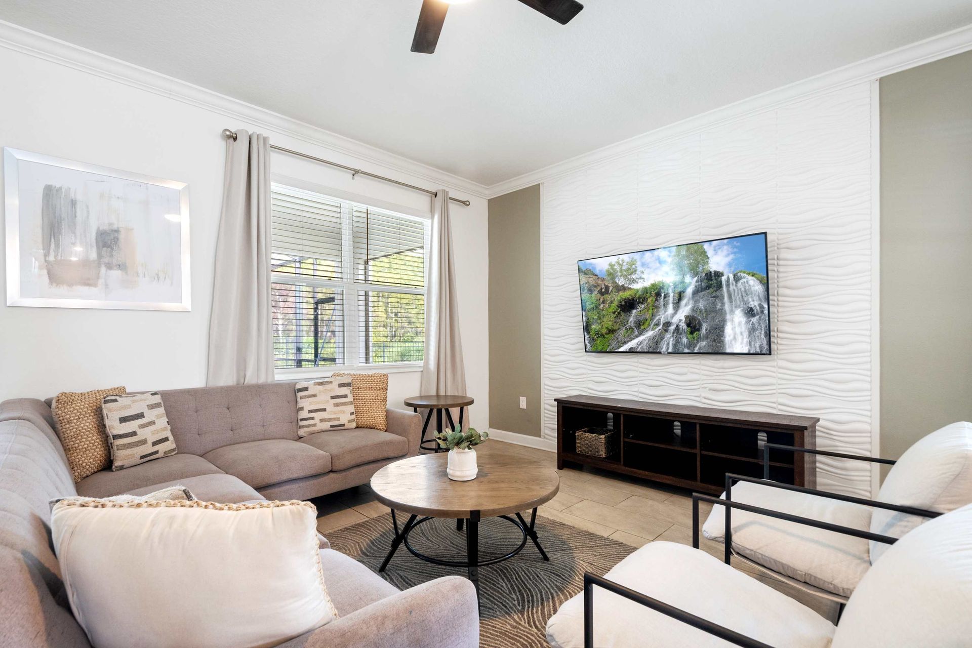Modern living room with a huge TV and ample, comfortable seating.