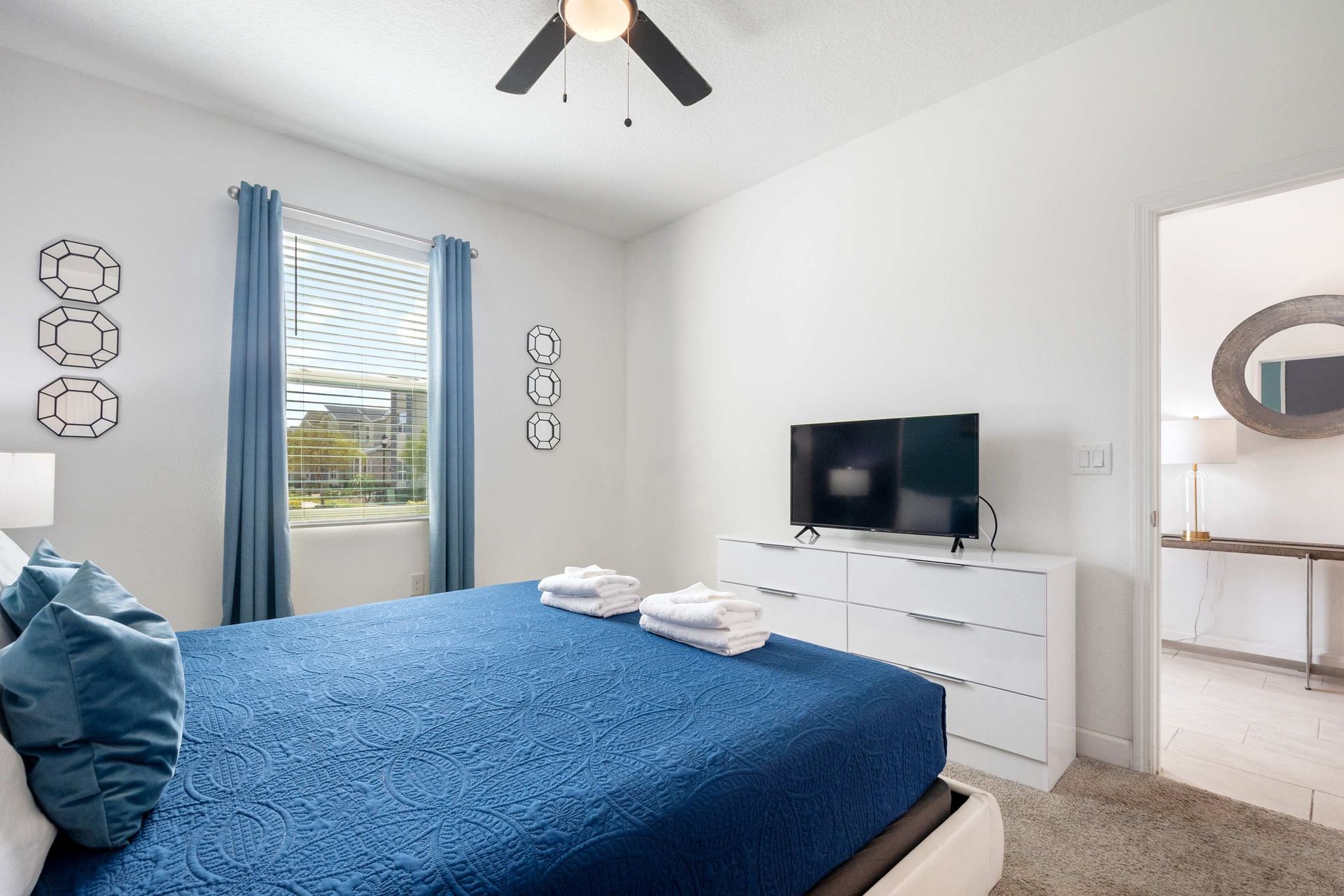 Bright queen room with a cool blue palette, TV, and en suite access.