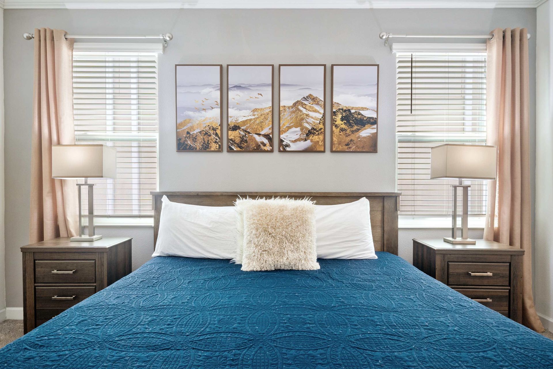 Calm and cozy King bed with a bright blue quilt and mountain art. 