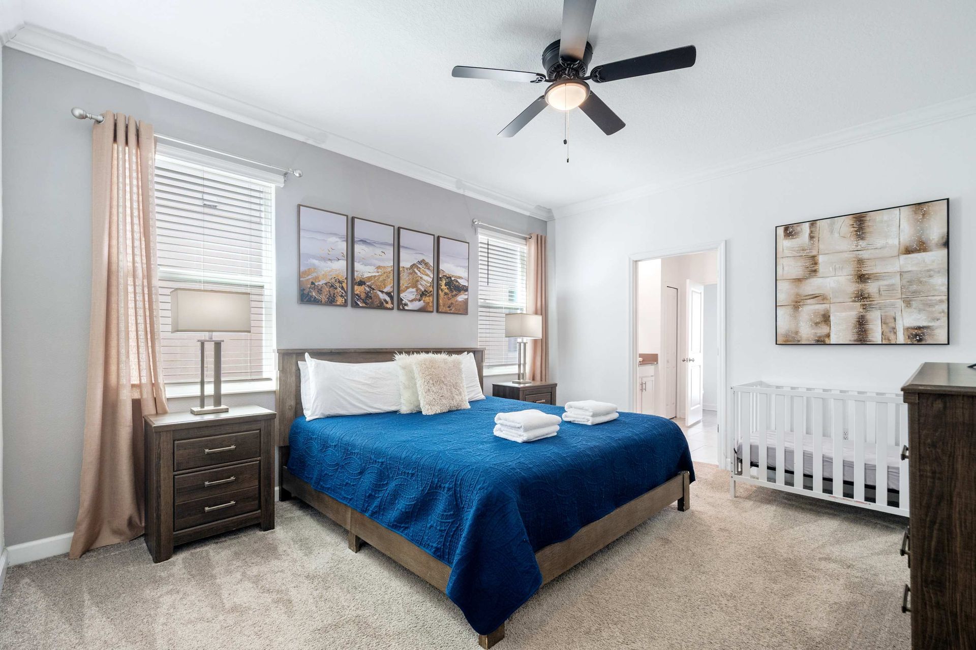 Spacious king suite with a crib, plush carpet, and stylish art.