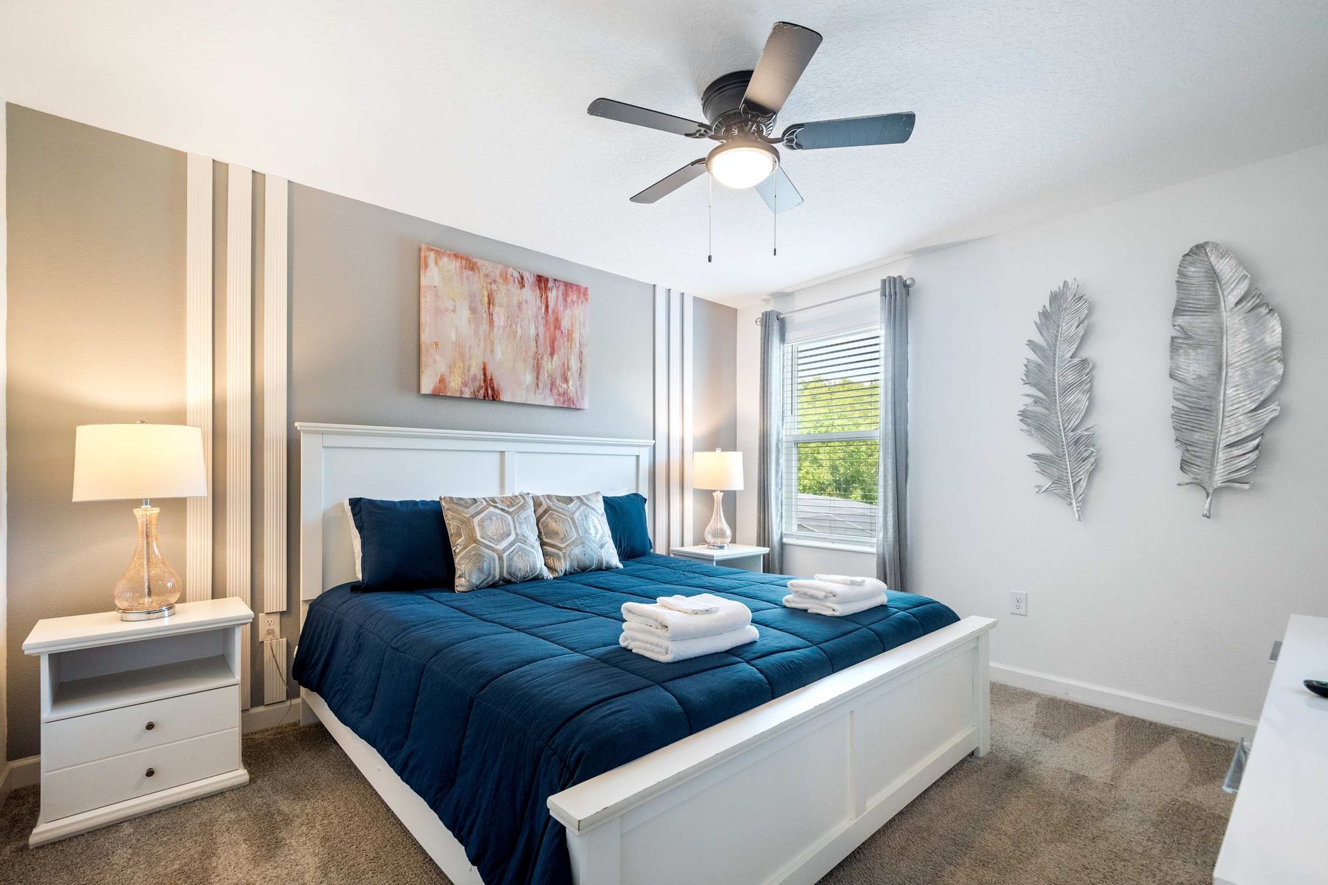 Stylish King bedroom with bold navy bedding and chic accent wall. 