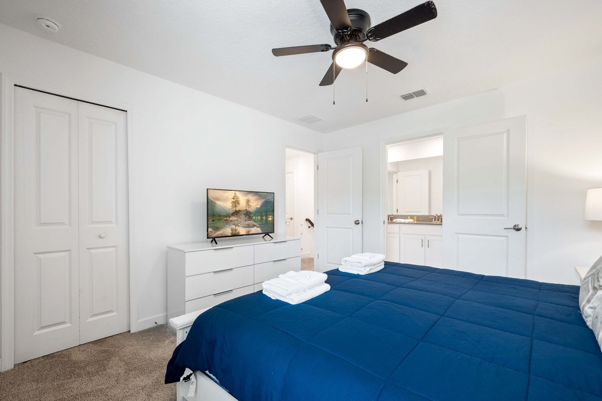 Bright bedroom with a comfortable bed, large TV, and ensuite bath access. 