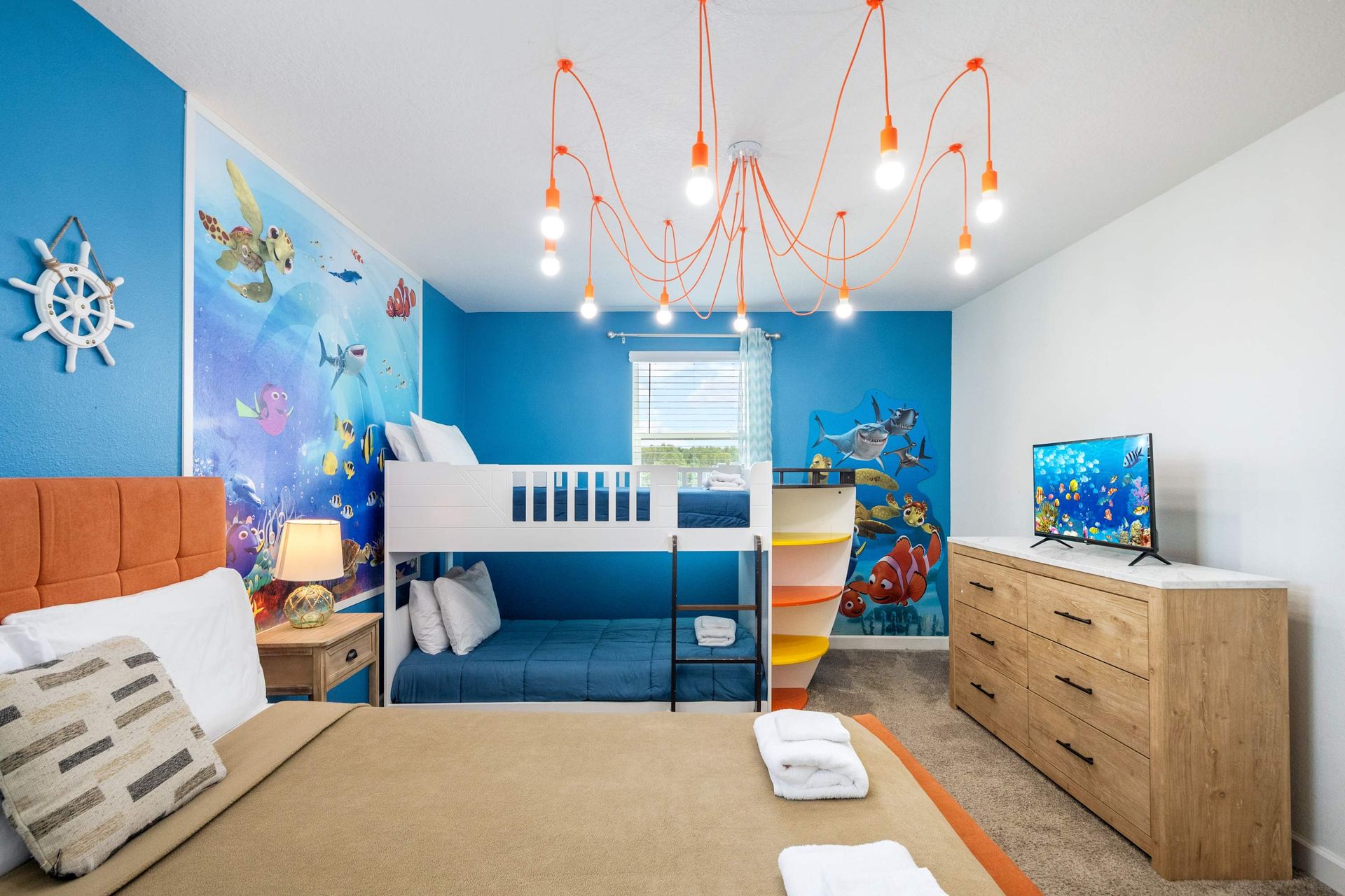Fun mural and unique spider chandelier in a colorful kids' suite.