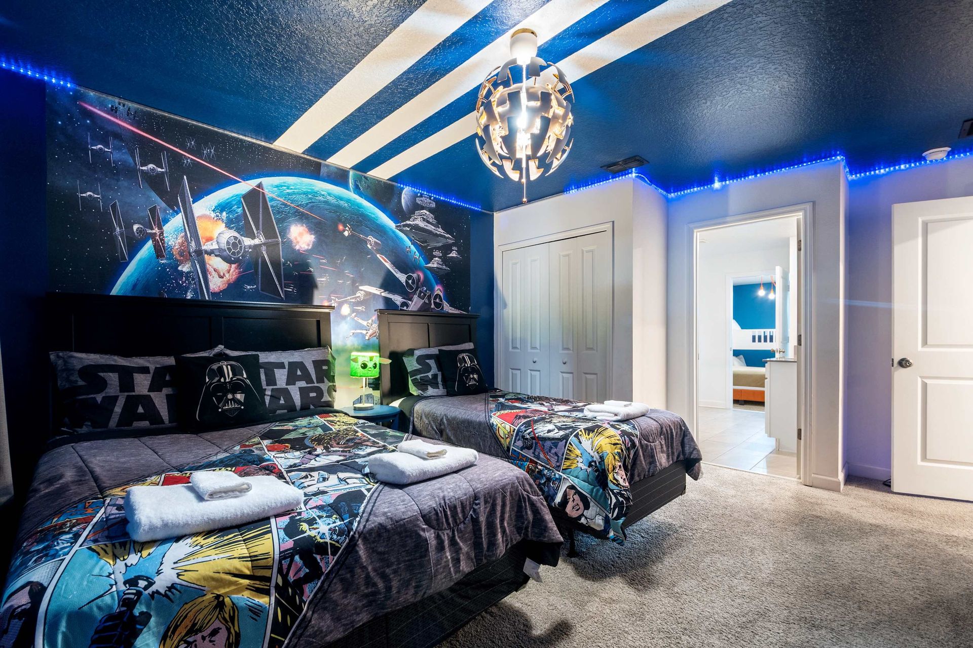 Twin beds under an epic STAR WARS mural and blue ceiling light. 
