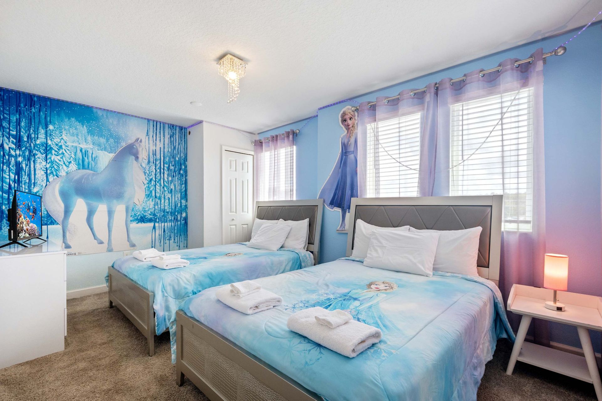 Twin beds in a Frozen-themed room with glitter mural and ice blue tones.