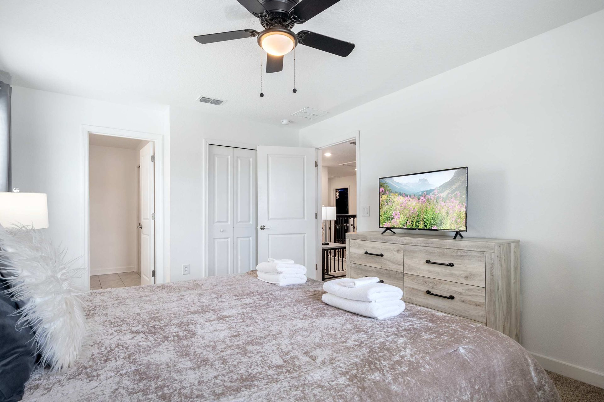 Plush king bed, ceiling fan, and large TV for a relaxing stay. 