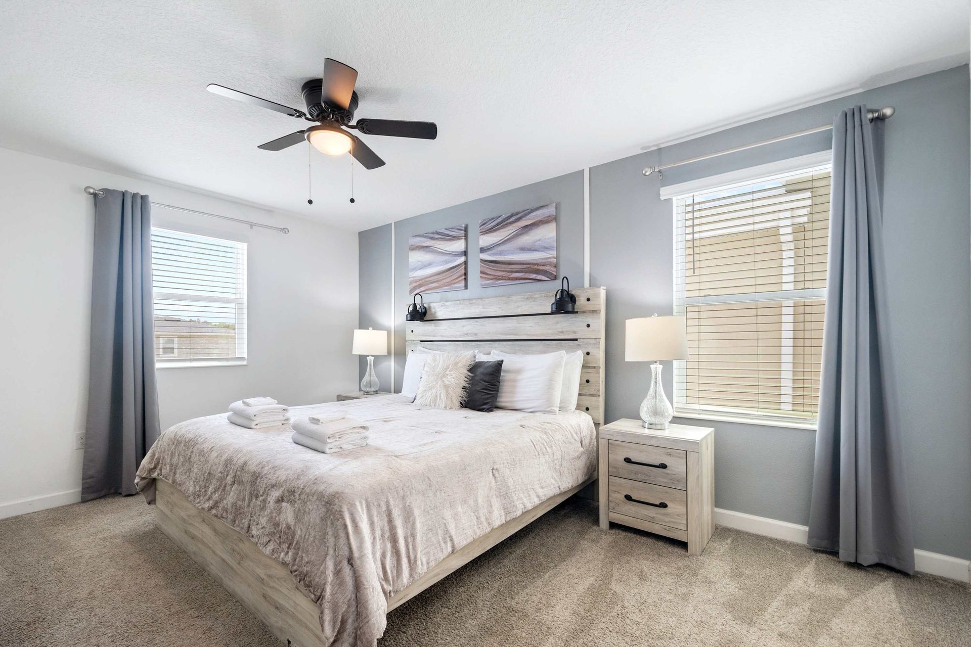 Serene queen room with chic paneling, subtle gray tones, and ceiling fan.
